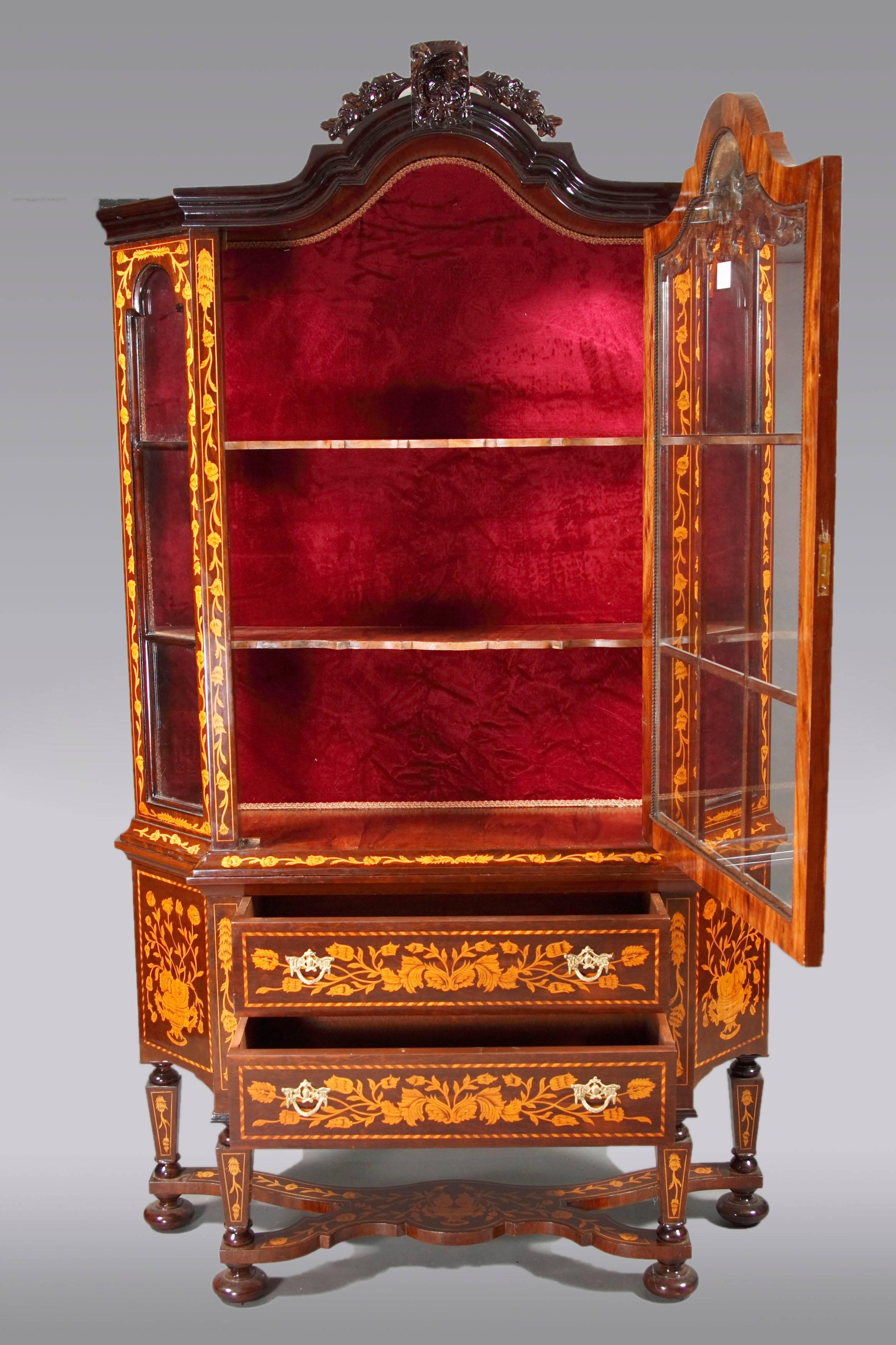 Light mahogany and maple on solid wood. Very rich, Baroque inlaid work. High-corpuscular body. On balustrade-shaped legs connected with an X-shaped ridge. Above two-wise frame base with profiled cover plate. Three-sided sprout-glazed, single-door