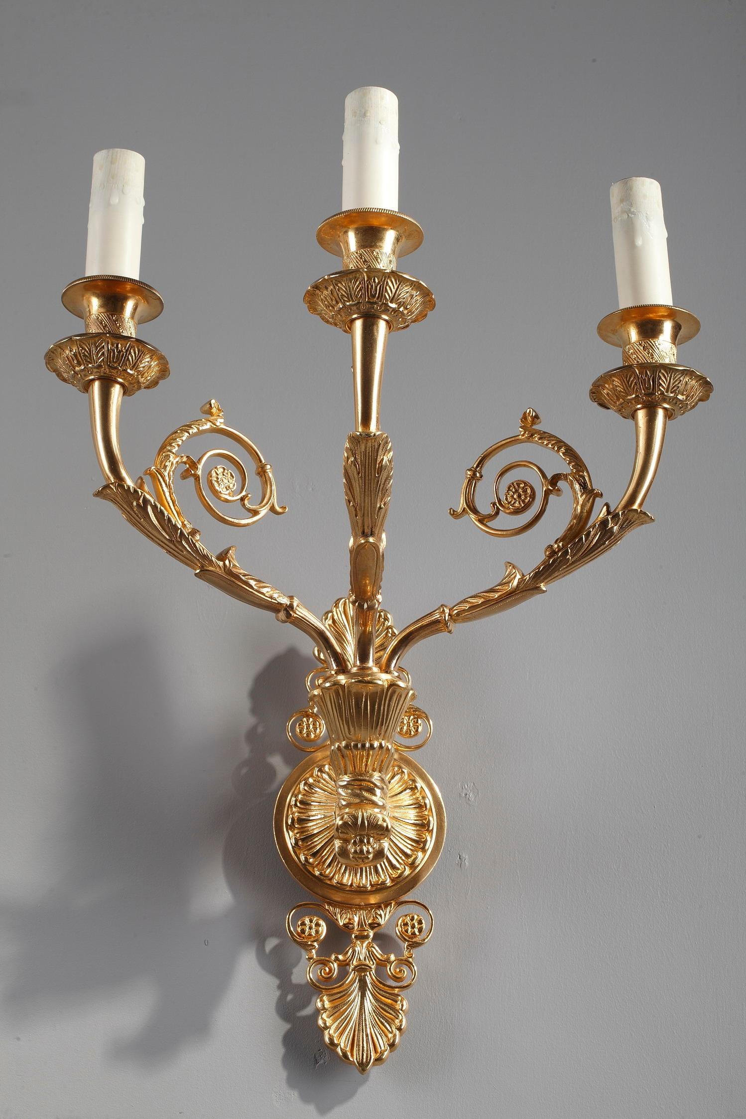 Pair of Ormolu wall sconces with three lights centered on a medallion. They are decorated with Charles X motifs: palmette, acanthus leaves, small flowers and scrolls. The upper and lower parts of the lamps are pierced. The lights are finely chiseled