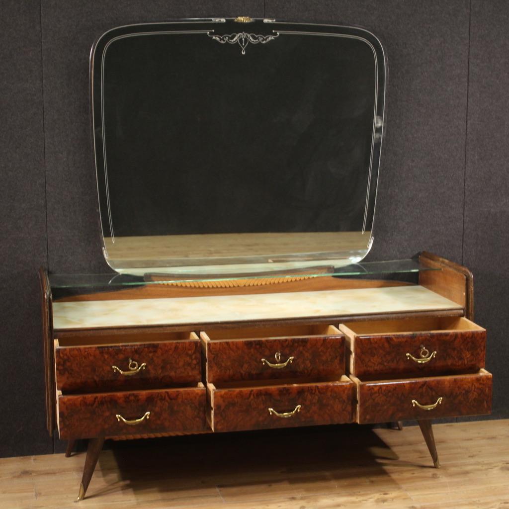 Chest of drawers with mirror, Italy, mid-20th century. Italian design furniture of fabulous line, carved and veneered in walnut, briar and fruit woods. Chest of drawers equipped with six large drawers adorned with gilded brass handles, painted glass