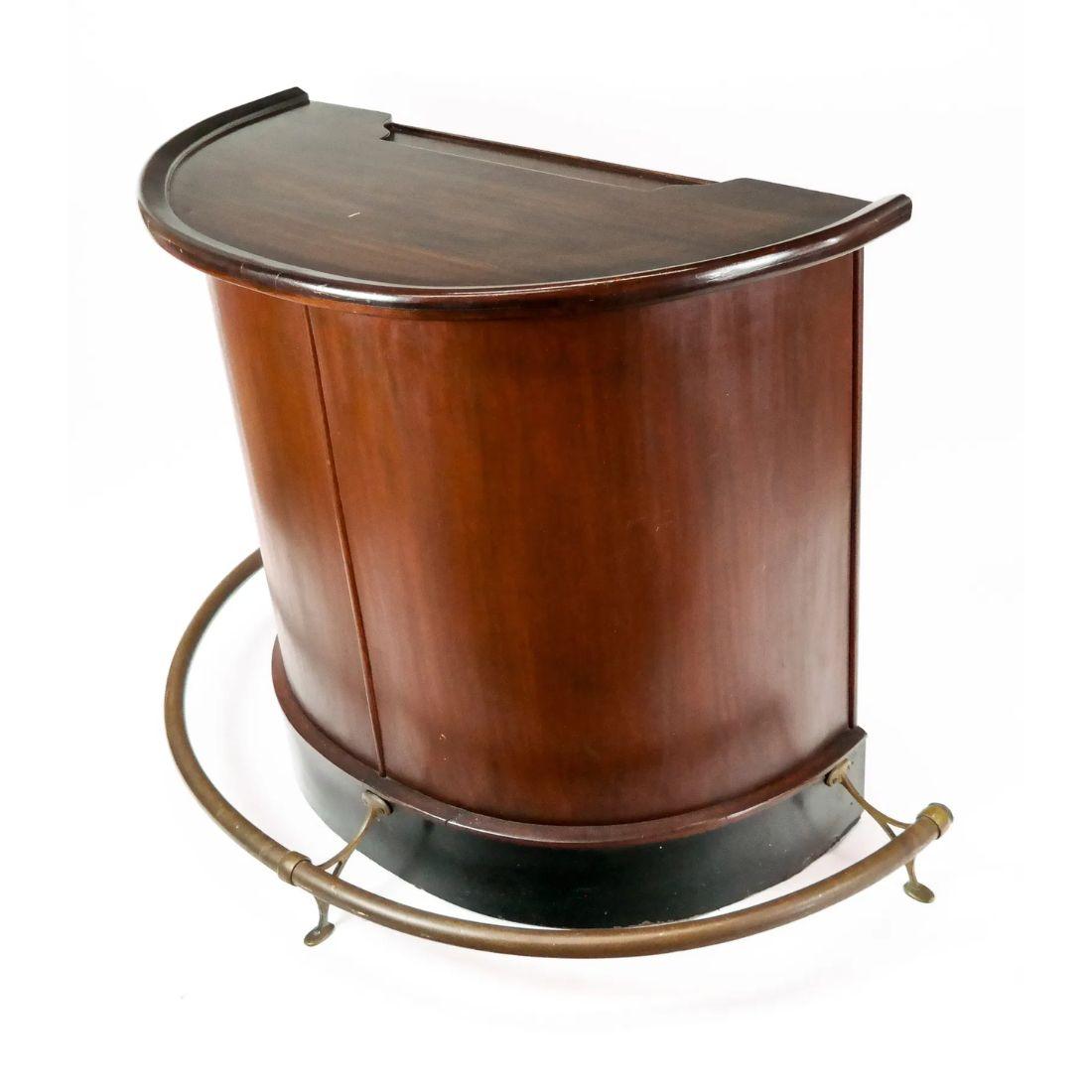 Graceful curves meet timeless craftsmanship in this walnut demi-lune dry bar. Designed with entertaining in mind, the rich walnut body is complemented by a polished brass foot rail at the base adding both function and a touch of vintage glamour. The