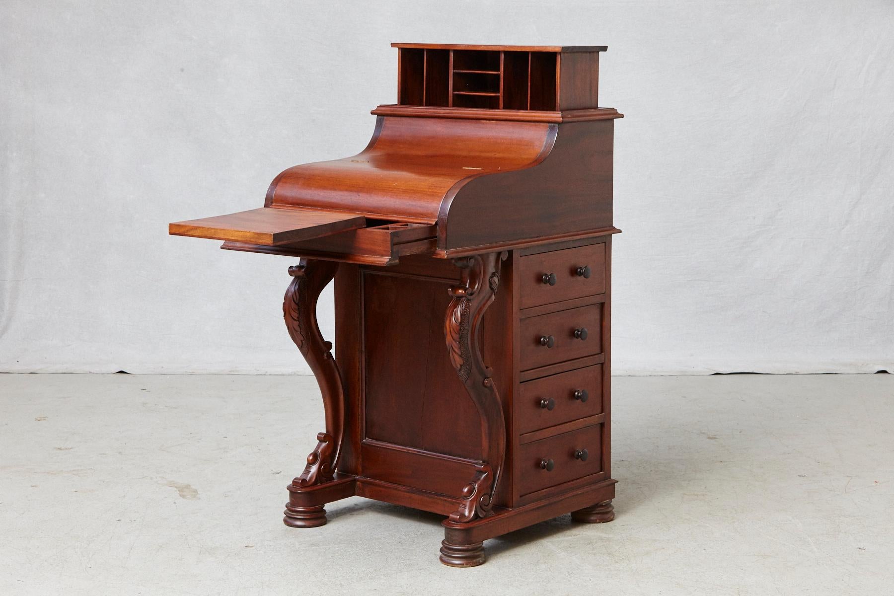 20th century walnut Davenport desk with a piano top, a flip front, a spring loaded letter compartment released with a hidden latch in a lower drawer, a plentitude of drawers, pen trays and pigeonholes for storage. 
Four full width drawers on one