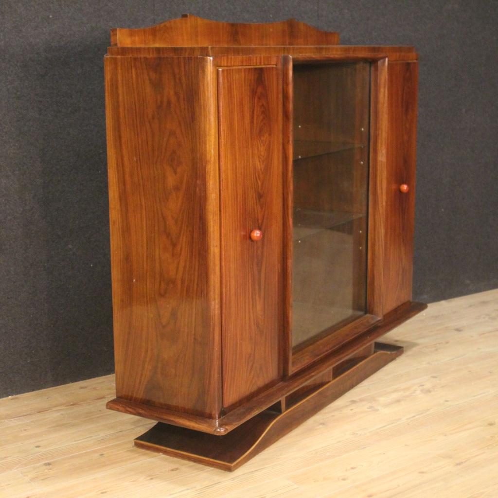 Italian vitrine from the mid-20th century. High quality furniture in rosewood, palisander, mahogany, walnut, maple and fruitwood. Showcase with three doors, two wooden side doors and a central sliding glass doors (see photo). Interior of the side