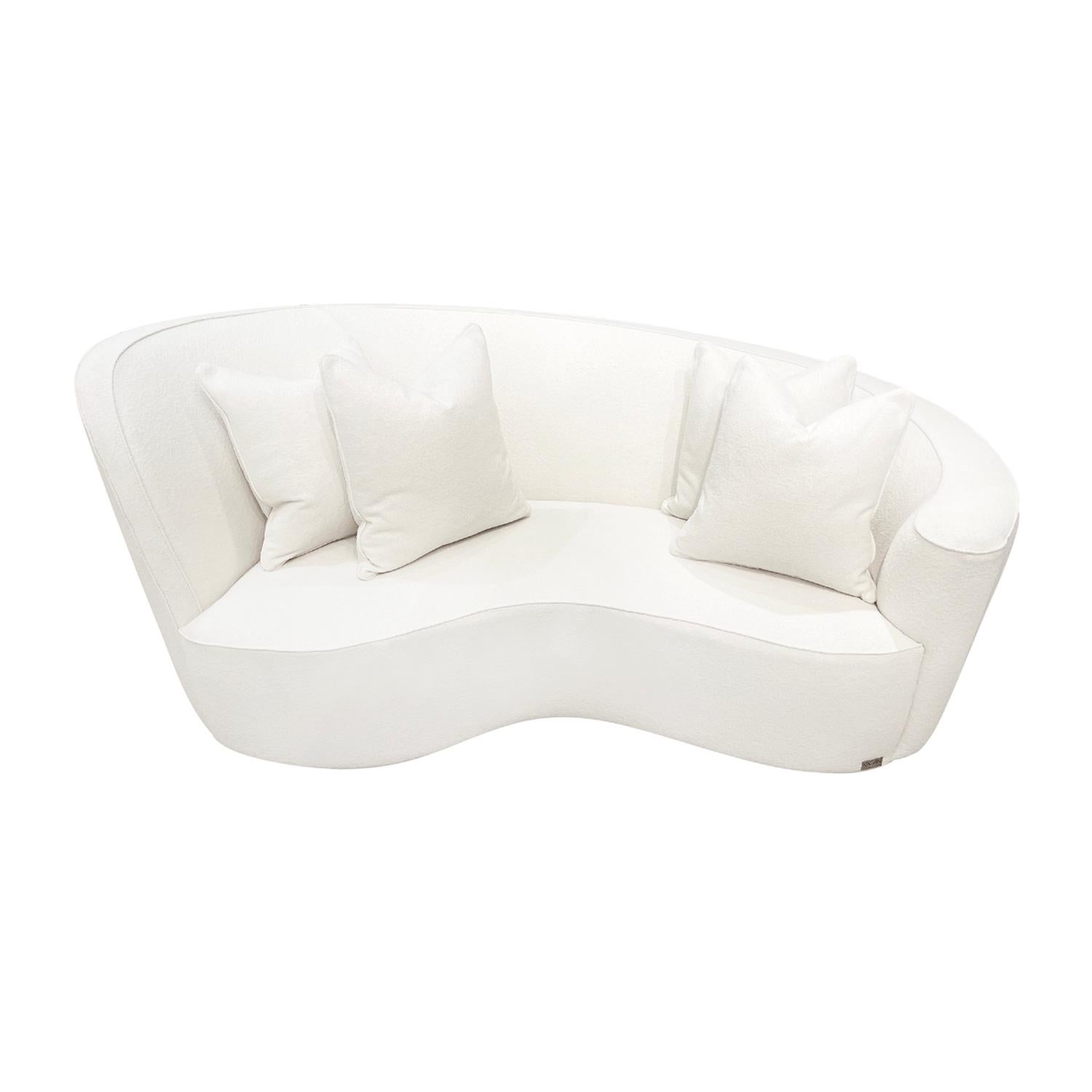 A vintage Mid-Century modern American four seater sofa with four pillows, designed by Vladimir Kagan in good condition. The high seat backrest of the settee, canapé curves seamlessly into a wide and tall armrest. Newly upholstered in a white bouclé