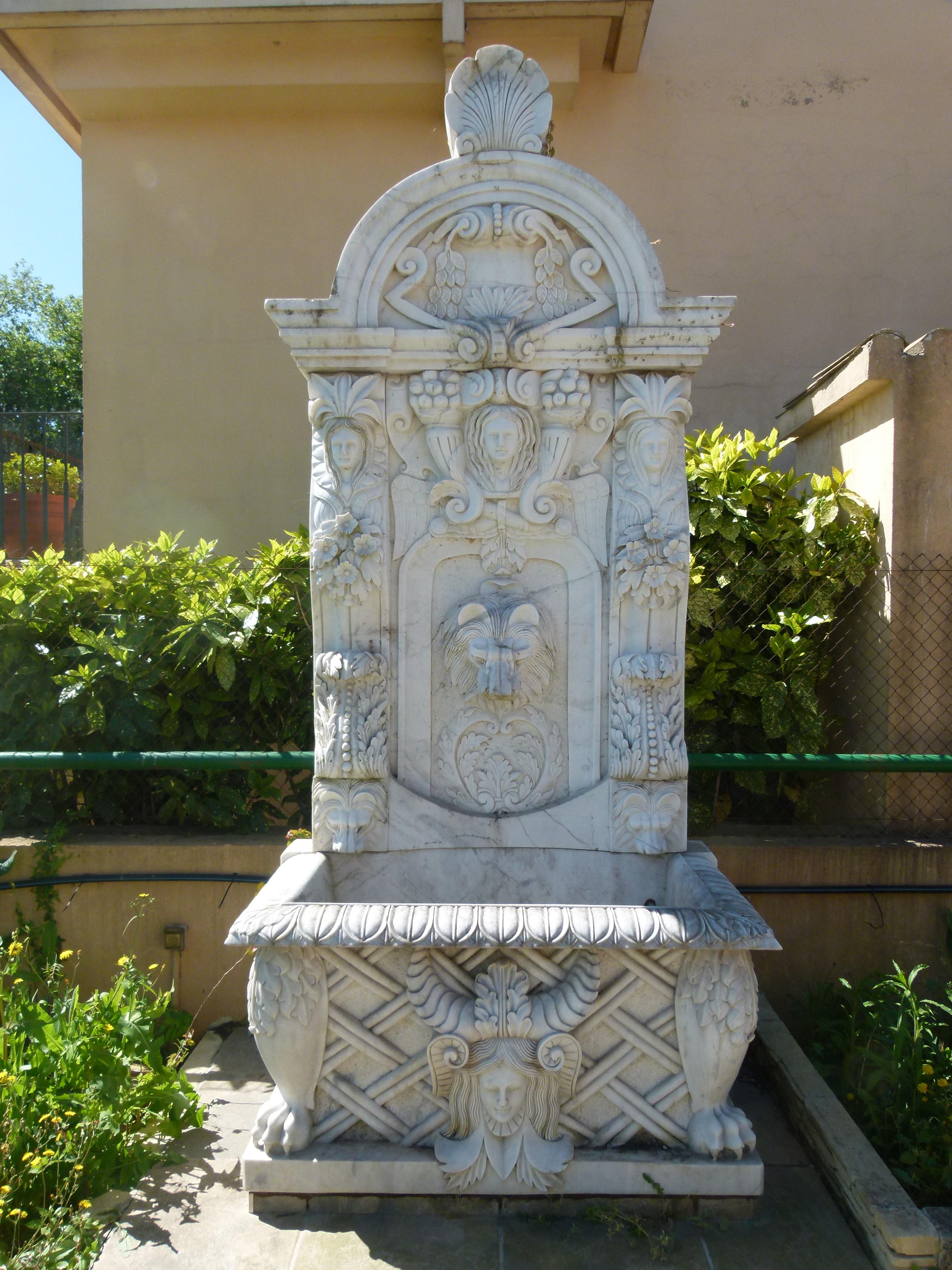 Hand carved white marble wall fountain in Classical style, made in the fifties in Spain.
Decorated with three women's heads figures on the upper part, a lion head figure in the center used as water spout, more lions heads on both laterals of the