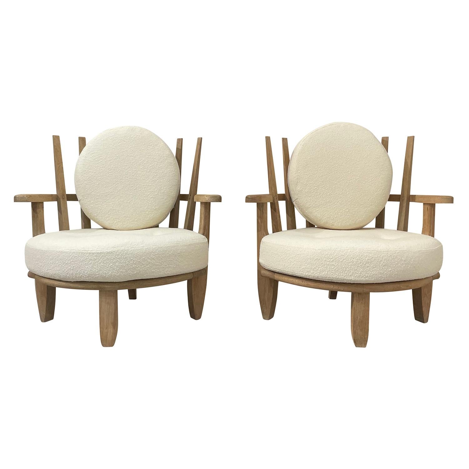 A light-brown, vintage Mid-Century Modern pair of lounge chairs made of hand carved bleached Oakwood, designed by Guillerme et Chambron in good condition. The particularized center chairs are composed with an oval back cushion, pillow. The seat