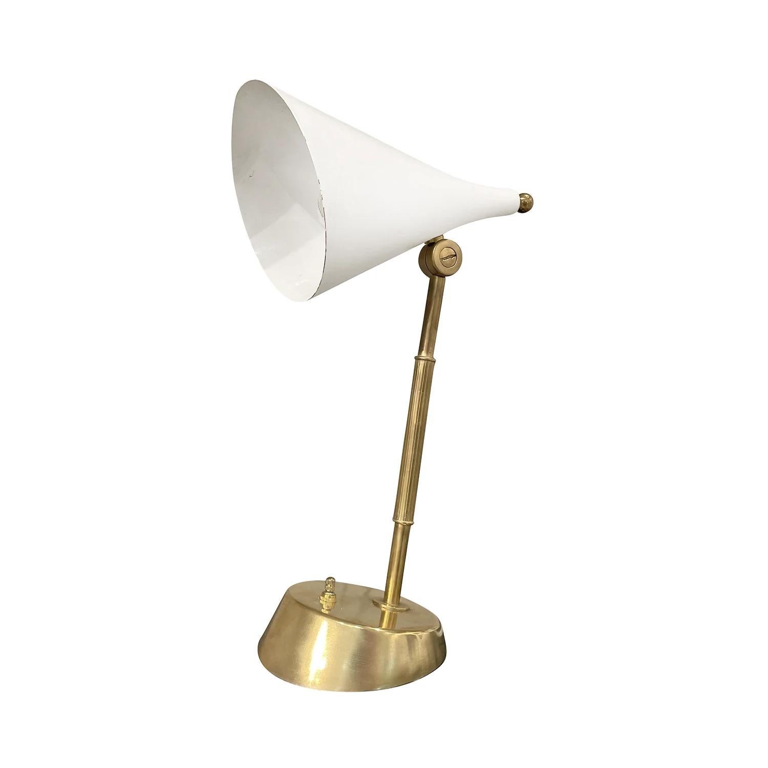 A vintage Mid-Century Modern Italian desk lamp made of hand crafted metal and polished brass, in good condition. The table light is composed with a white conical mount lacquered aluminum shade, supported by a curved brass arm, standing on an