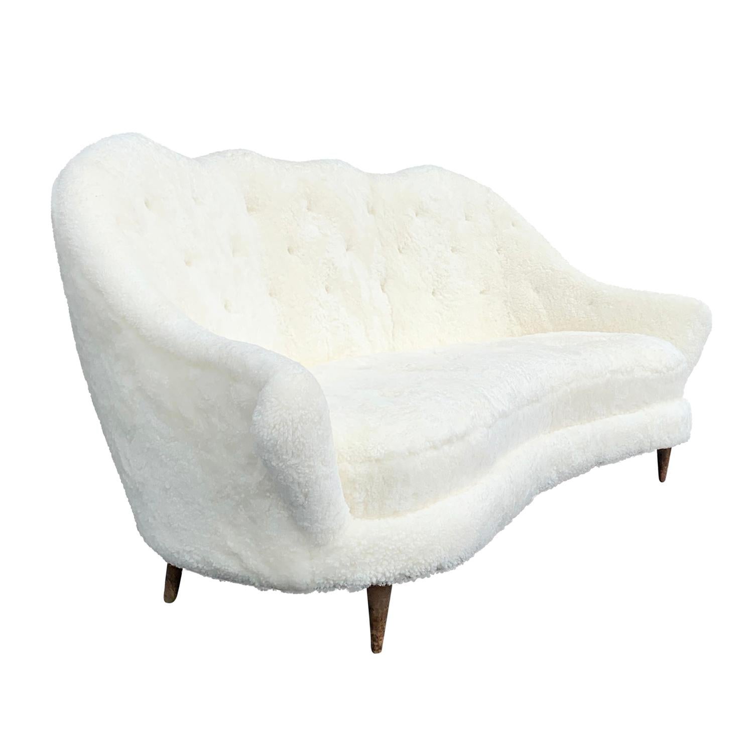 A vintage half-rounded Mid-Century Modern Italian three-seat sofa or divano made of Beechwood. Designed by Paolo Buffa in good condition. Newly upholstered in white natural sheepskin. The seat backrest has slight curves with gently outstretched