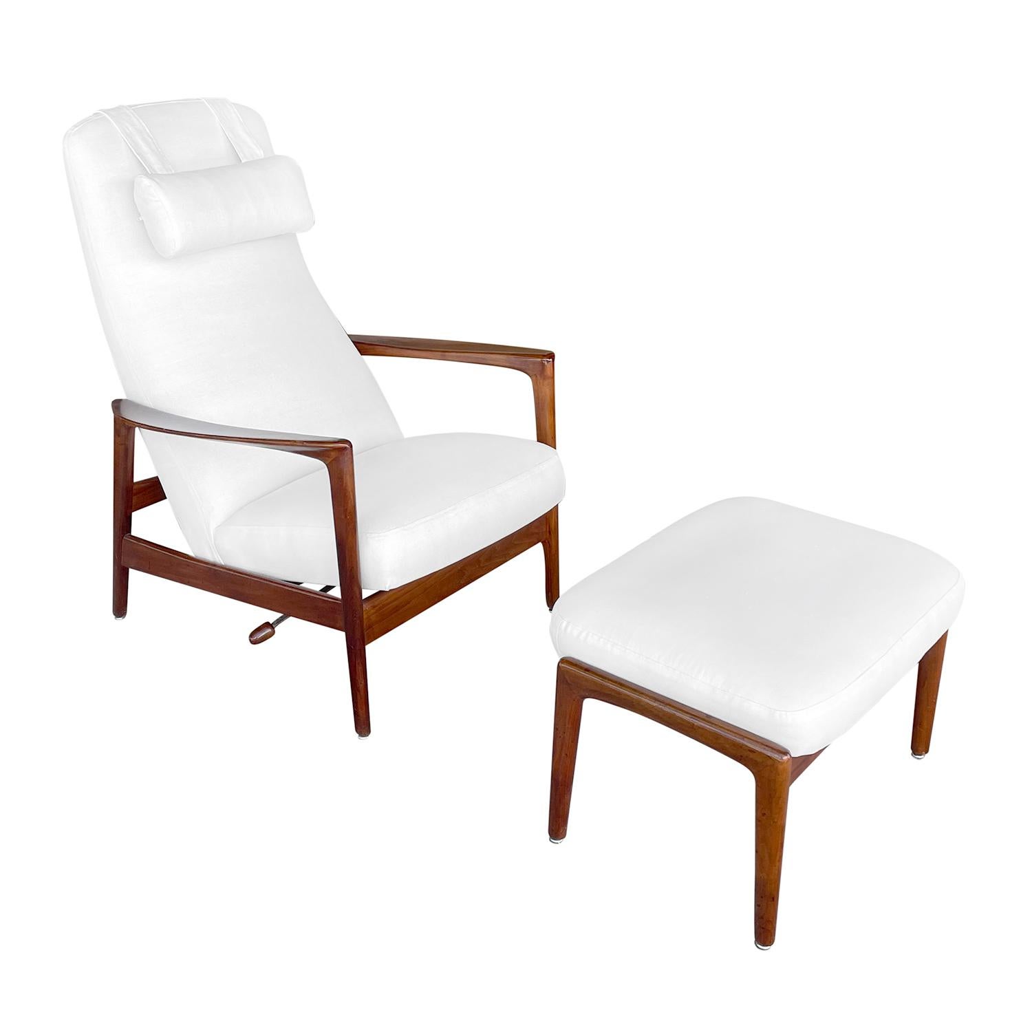 A vintage Mid-Century Modern Swedish armchair or high back recliner with a head rest and an ottoman, made of hand carved Walnut, produced by DUX in good condition. The reclining arms are slightly curved, standing on four angled wooden legs which are