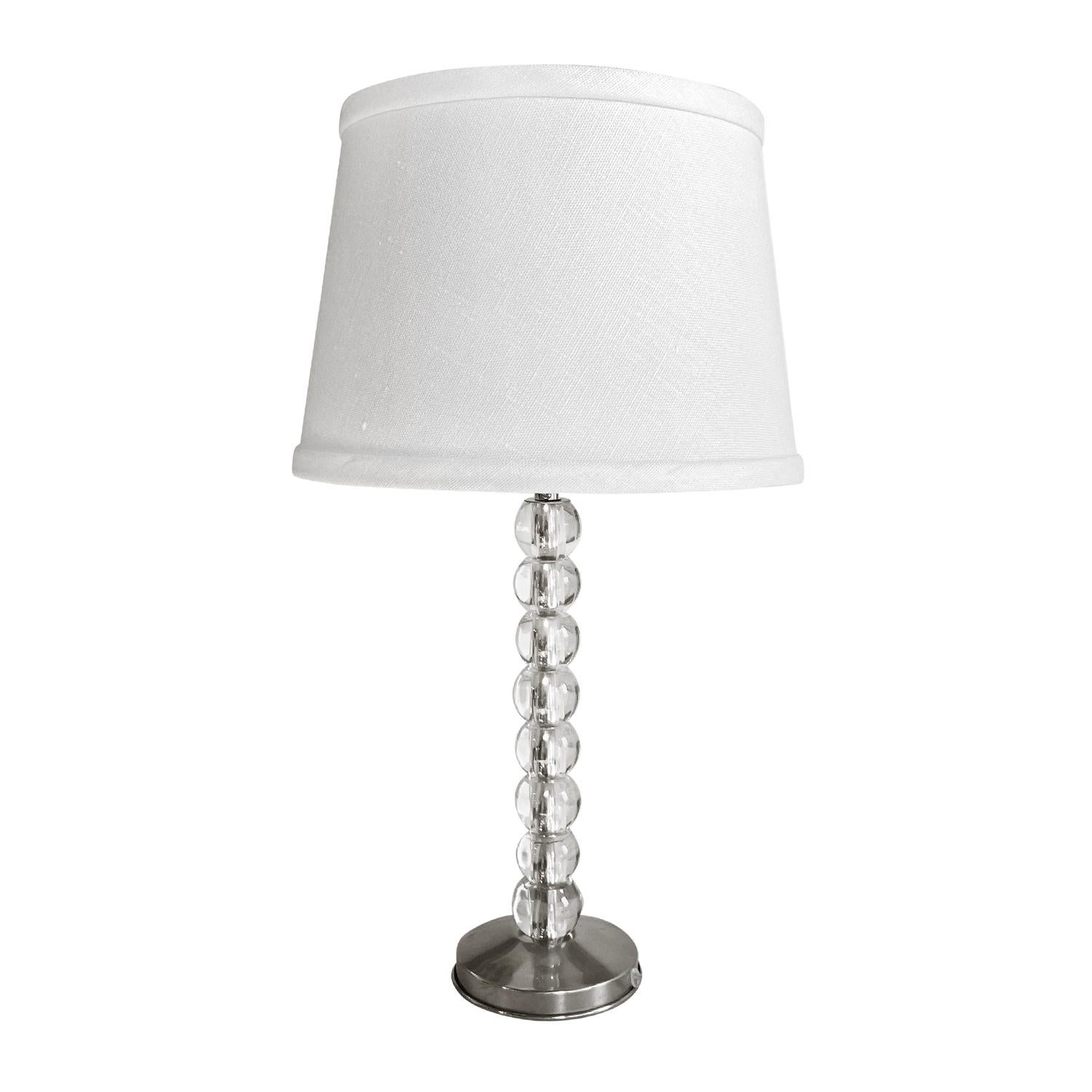 A vintage Mid-Century Modern Swedish table lamp made of hand blown crystal glass, detailed with a white shade, produced by Orrefors in good condition. The Scandinavian desk light is comprised of stacked, round glass pieces, a single light socket,