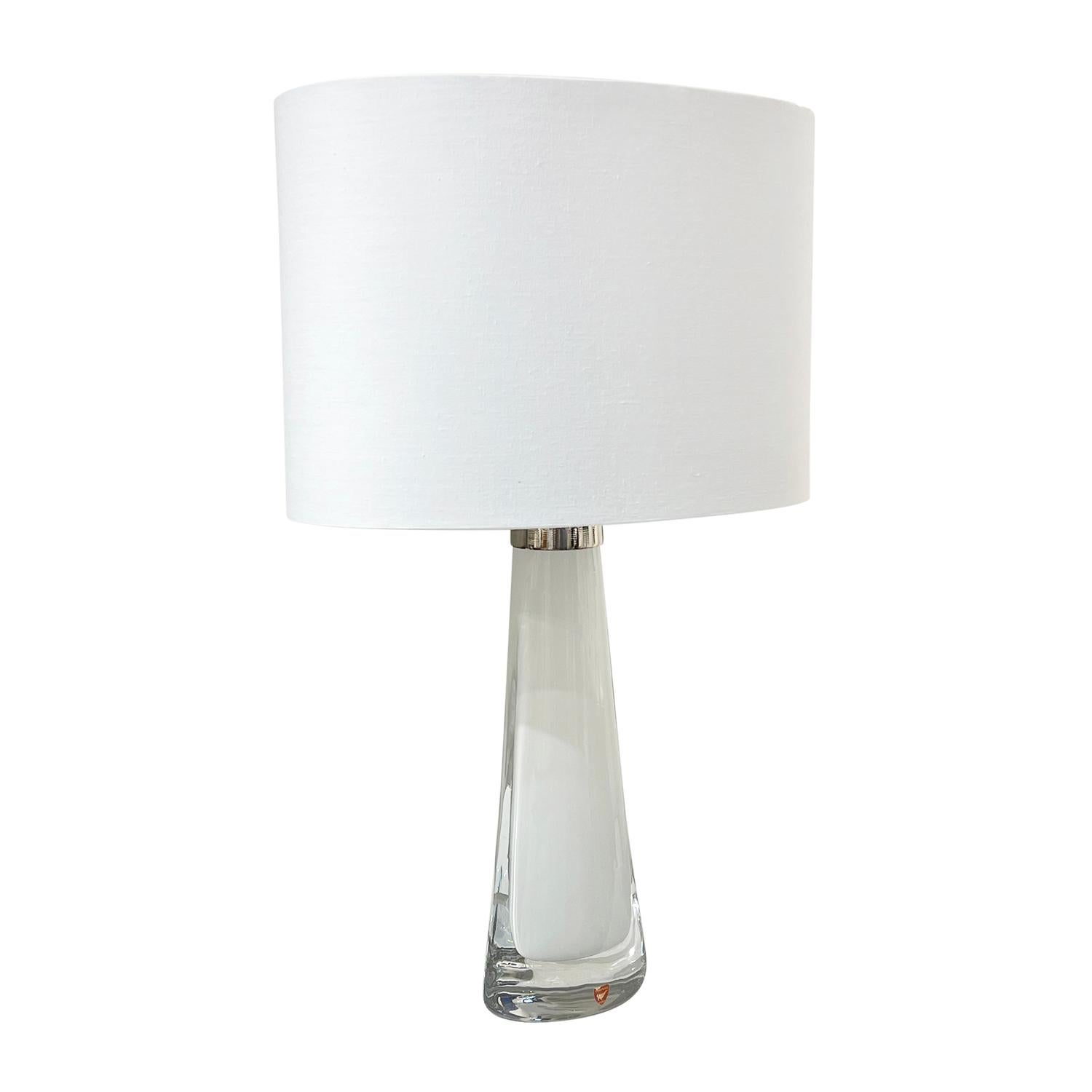 A half round, vintage Mid-Century Modern Swedish table lamp with a new white oval shade, made of hand blown Orrefors glass, the beam is enhanced with a chrome ring, featuring a one light socket in good condition. The white undercoat Scandinavian