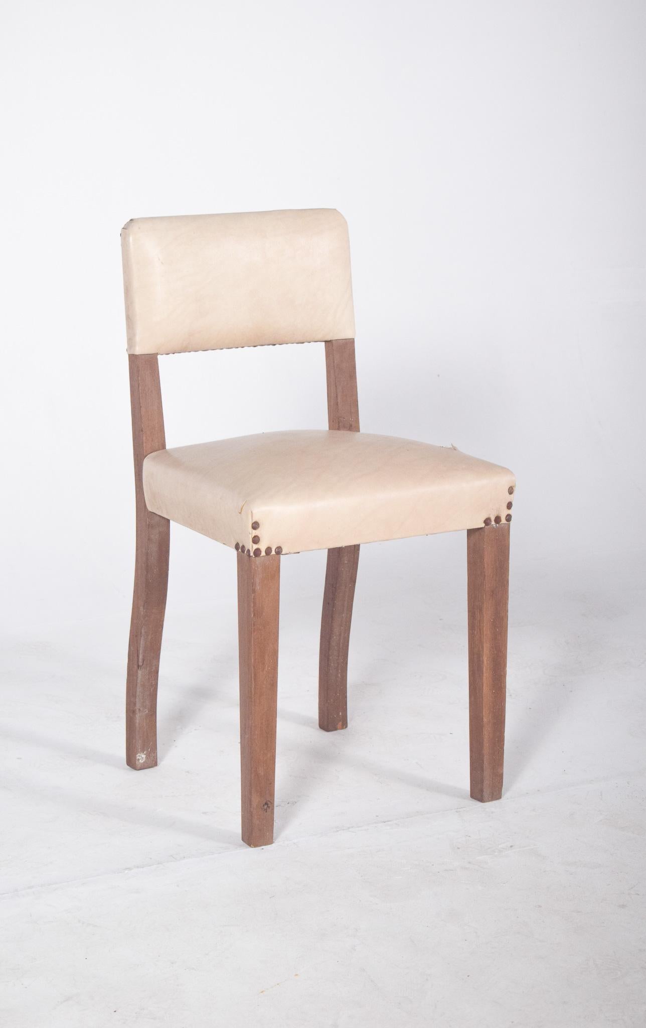 Chair upholstered in white. With a simple, sturdy structure, back and seat upholstered in synthetic leather, fixed to the wood with visible metal studs, giving it a functional character with a decorative handmade touch. The straight legs at the