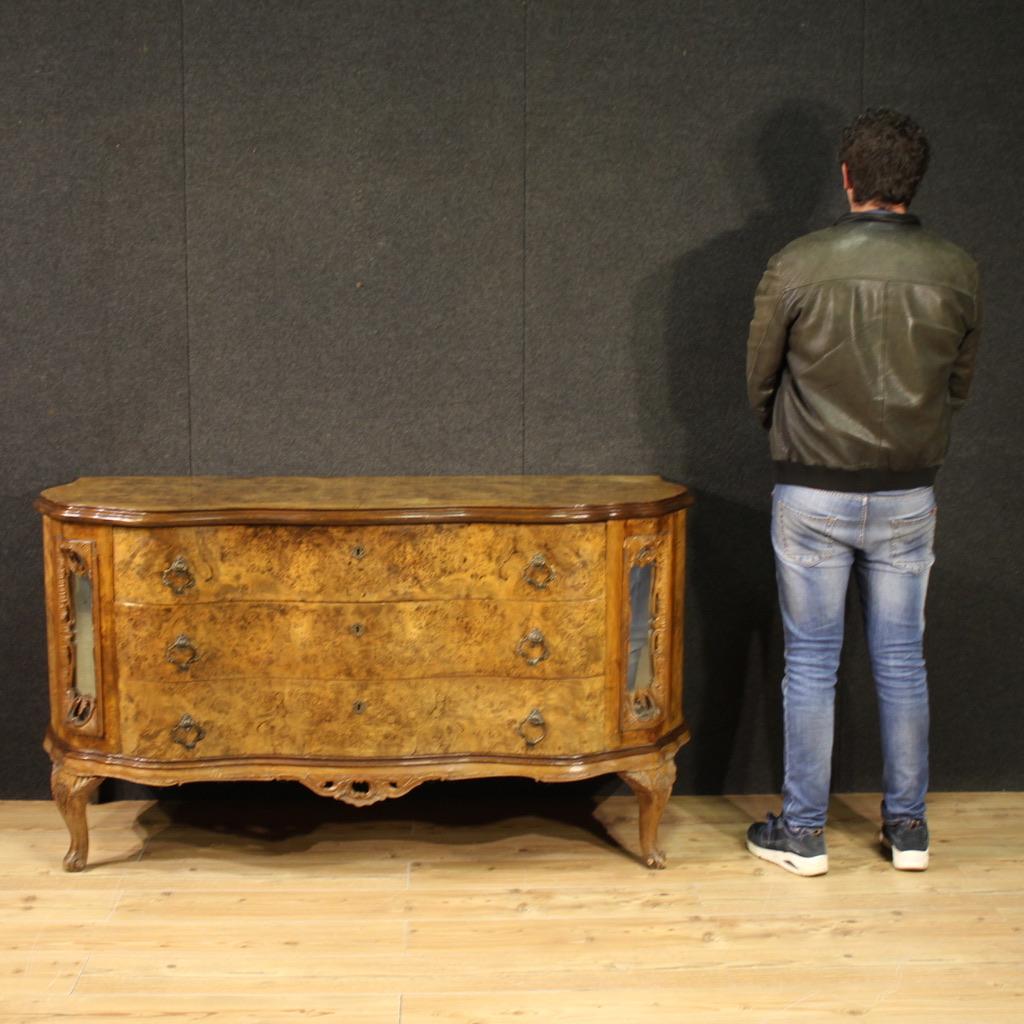 Large Italian chest of drawers from the mid-20th century. A curved furniture, carved in walnut, burl and beech with mirrors set into the side decorations, of excellent quality. A chest of drawers with three large drawers and a wooden top in