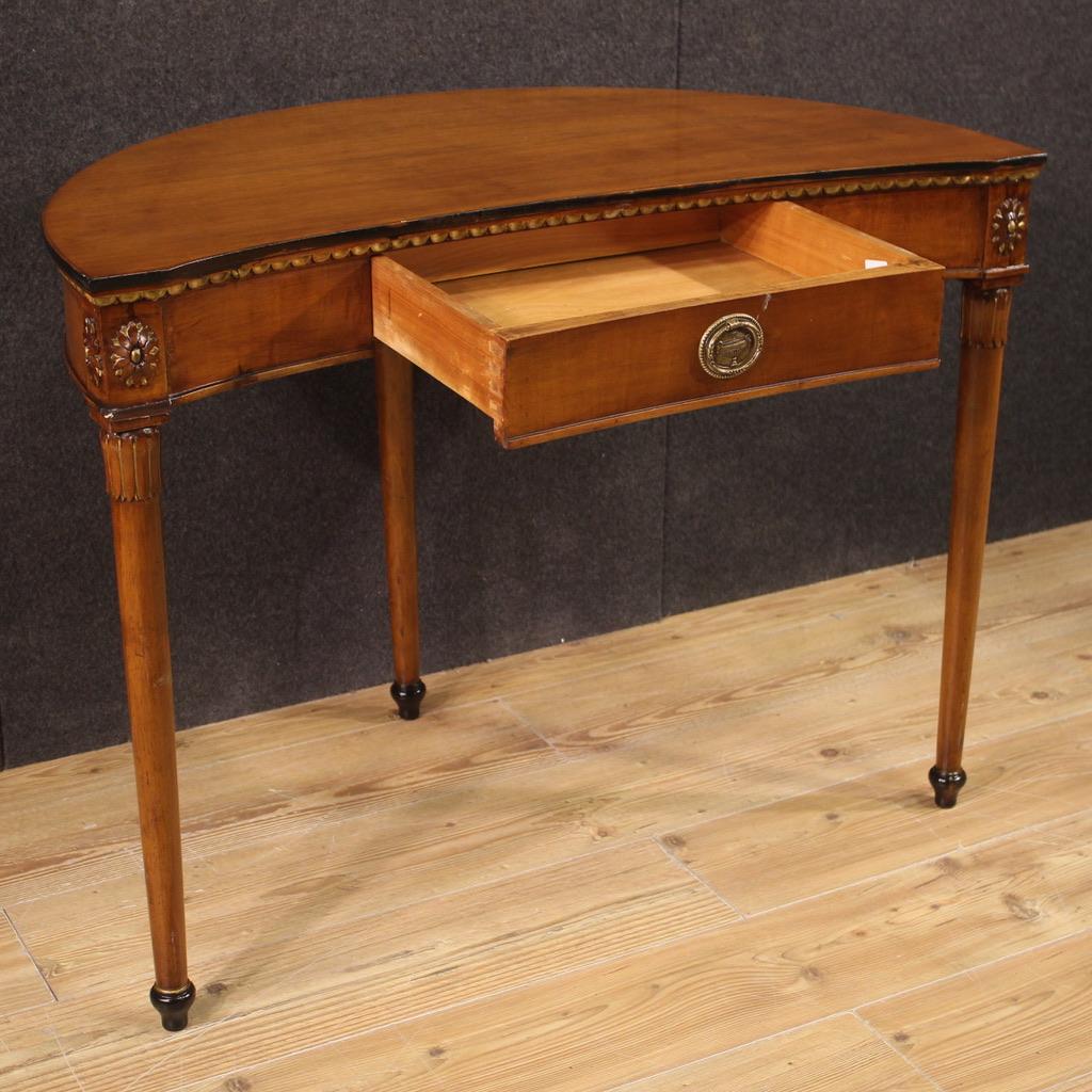 Italian writing desk from the mid-20th century. Empire style half moon furniture, of beautiful line, carved and gilded in cherry wood, fruitwood and ebonized wood. Writing desk equipped with a front drawer of good capacity, resting on three solid