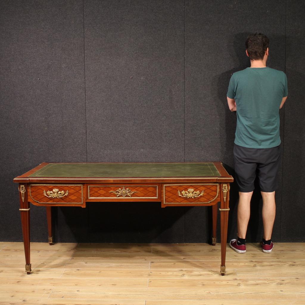 French writing desk from the mid-20th century. Louis XVI style furniture veneered in mahogany and walnut, rich in gilded and chiseled metal decorations. Finished desk for the center equipped with three large front drawers and supported by four solid