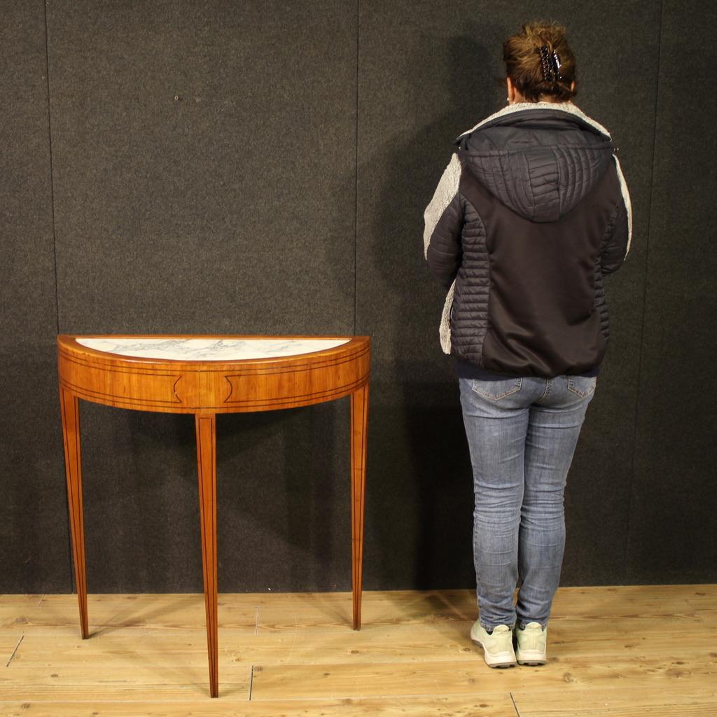 A mid-20th-century Italian half-moon console table. This Louis XVI-style furniture is carved and trimmed in cherry and ebonized wood, with an original inset marble top. The console table features tall legs, supported by three solid, inverted