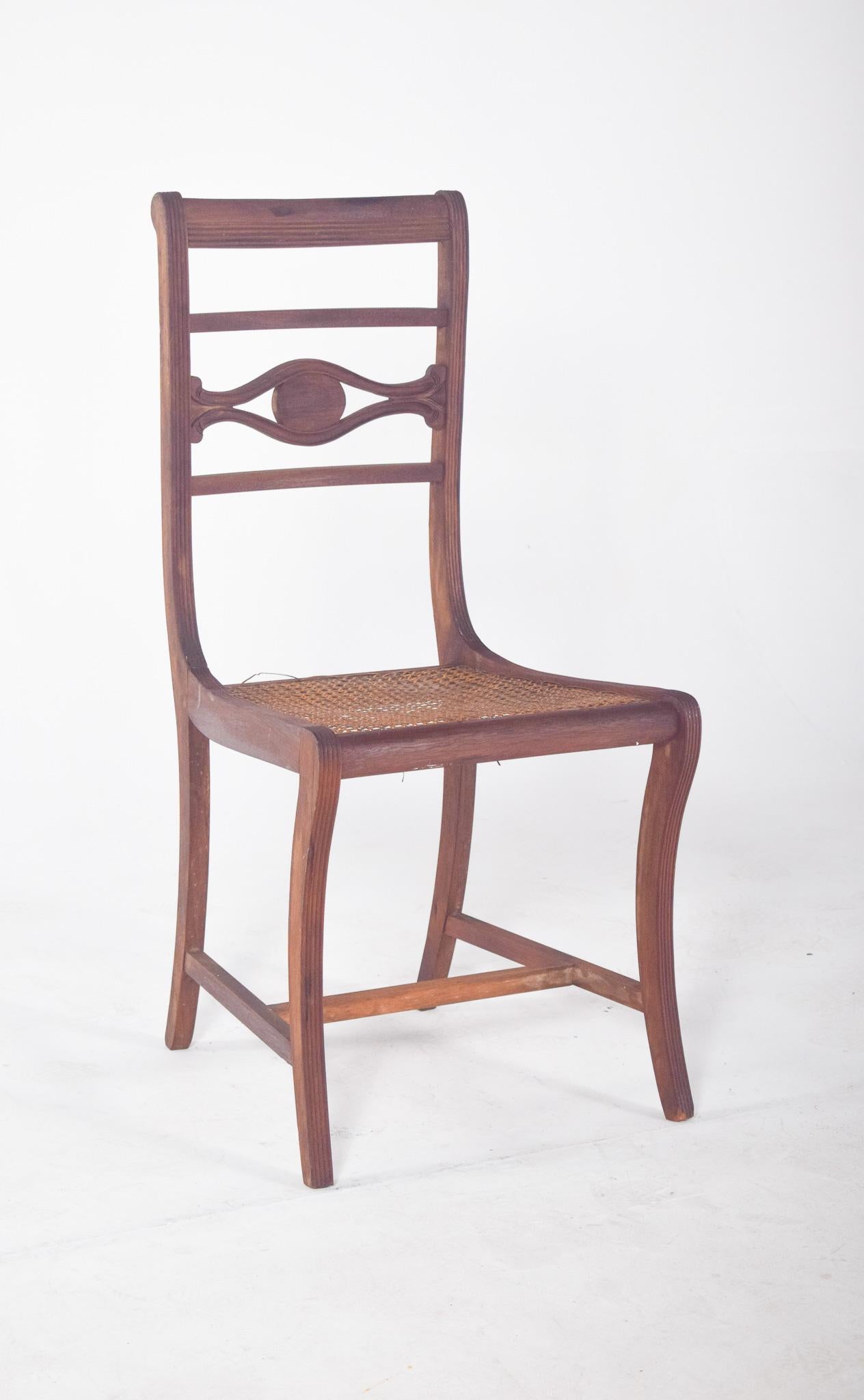 Chaise avec assise en paille. Le dossier est constitué de trois traverses horizontales, celle du milieu étant ornée d'un élément central creux en forme d'œil stylisé, aux lignes sinueuses et à la décoration simple
Les pieds avant sont légèrement
