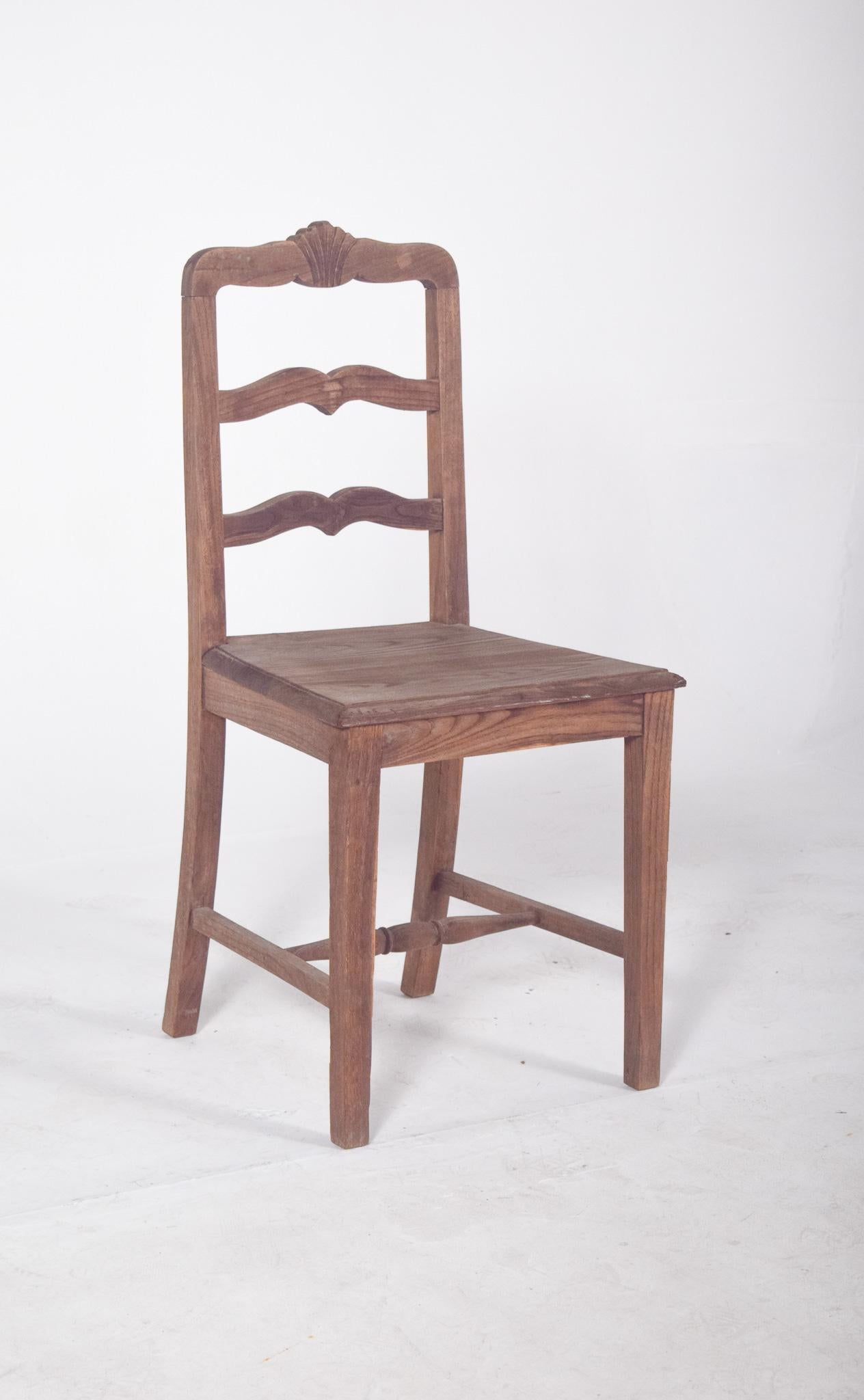 Wooden chair with wavy horizontal crossbars. The flat wooden seat and firm structure reveal a traditional construction, with lower crossbars that reinforce the stability of the piece, the front one being turned and the top one with a flower.
The