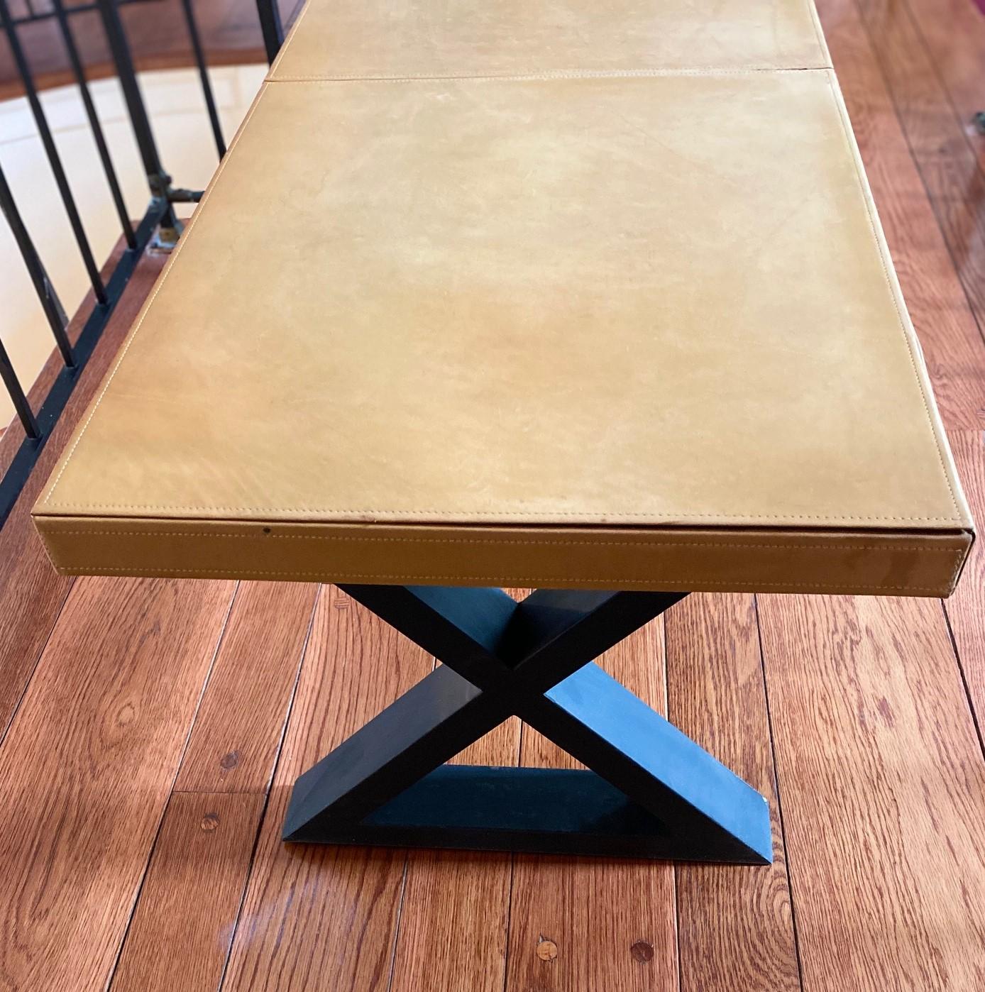 20th c., black X-form iron base with tan saddle stitched leather top, in style of Jean Michel Frank, (1895-1941, French), unmarked. This classic X-form base table packs substantial style punch. With saddle stitching on the top and sides, the leather