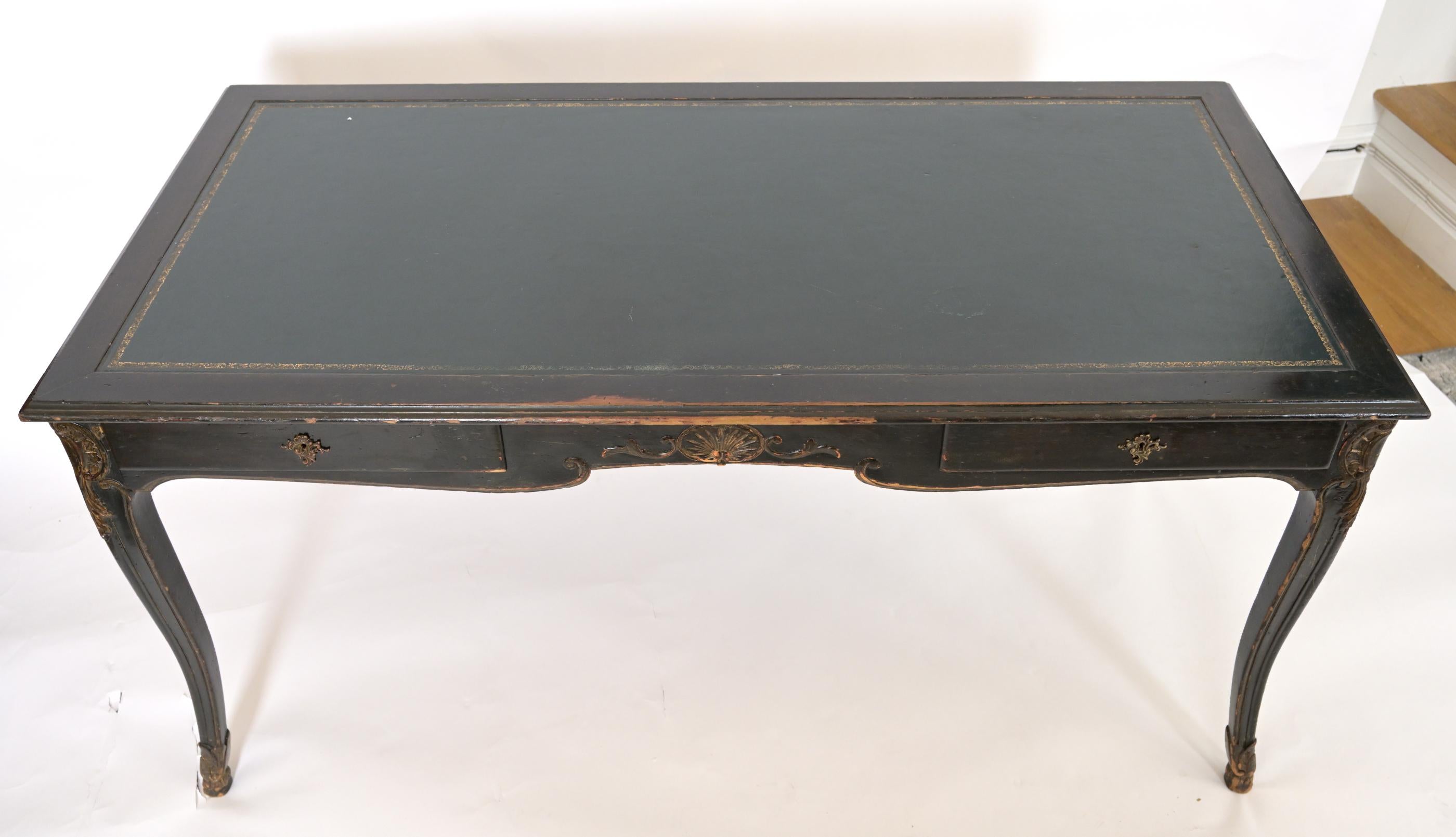 A Louis XVth style Yale Burge Writing desk having a leather top with two drawers, one on either side of the apron. The black veneer finished with scallop and wreath motifs sculpted into the wood. A leather top decorated with a gold painted border