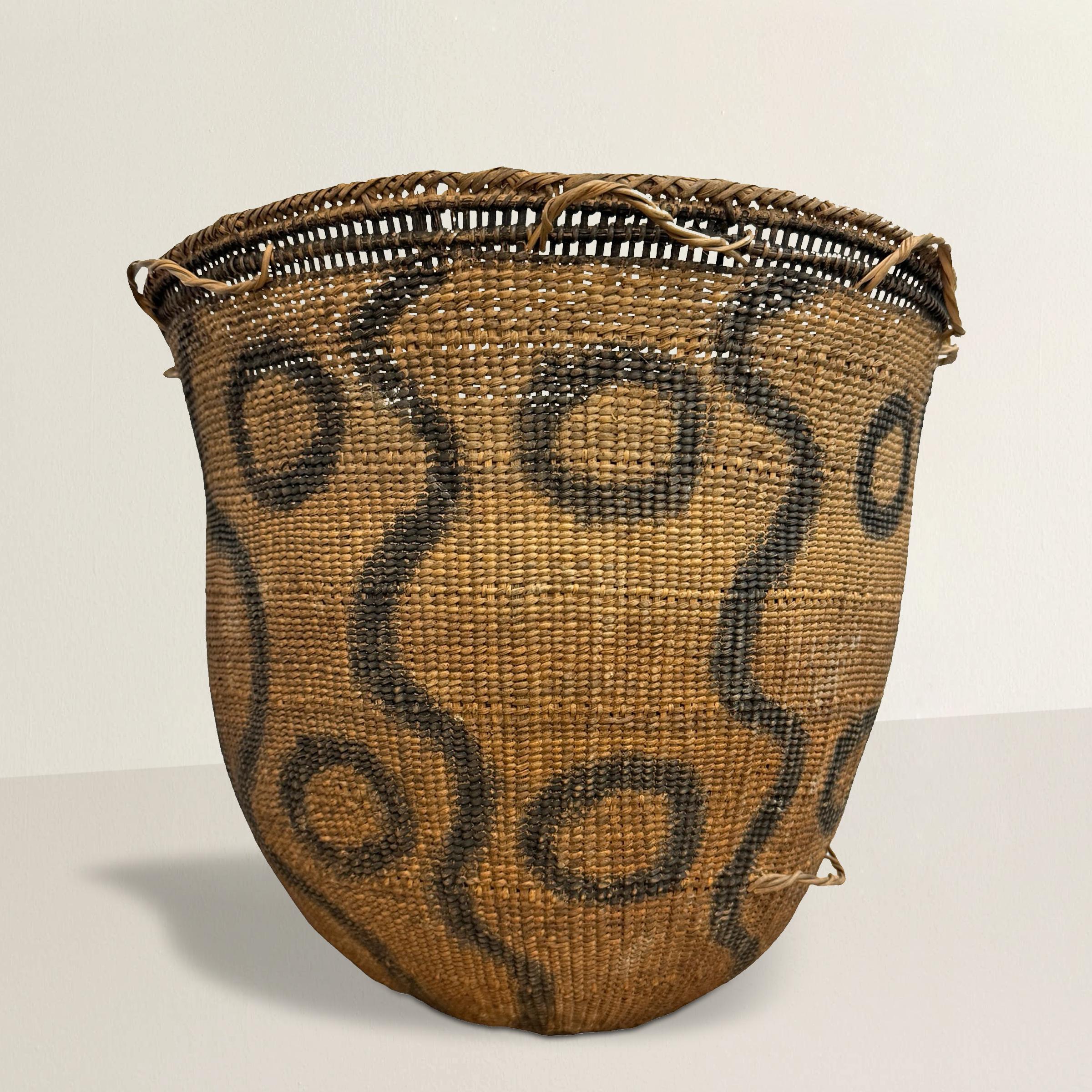 This 20th-century Yanomami basket is a remarkable example of traditional indigenous craftsmanship. Hand-woven in reeds and meticulously decorated with wavy lines and circles painted with ash, this basket is not only a practical tool but also a