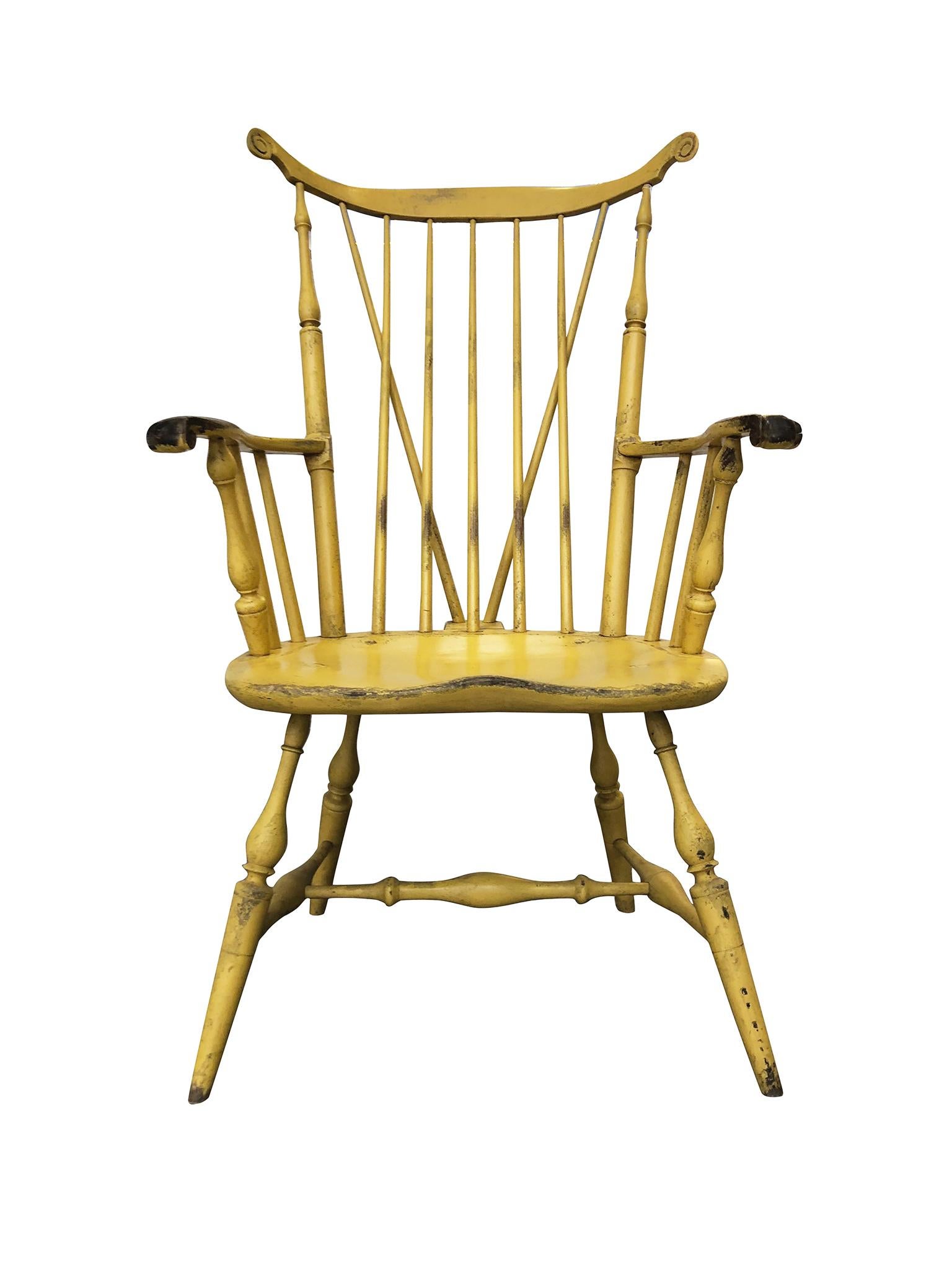 A Windsor chair handcrafted by Bill Wallick. Made from poplar wood and hand painted in a yellow coat that has been enriched with texture and wear over the years. The chair is faithful to a Classic Windsor design: a spindle fanback, a wing-tipped