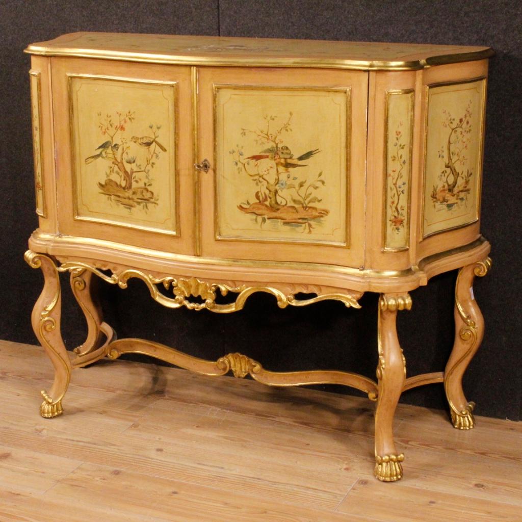 Venetian sideboard from the mid-20th century. Nicely carved, lacquered, gilded and painted wooden furniture with floral and animals decorations of great quality. High-legged sideboard with two doors and wooden top in character of good measure and