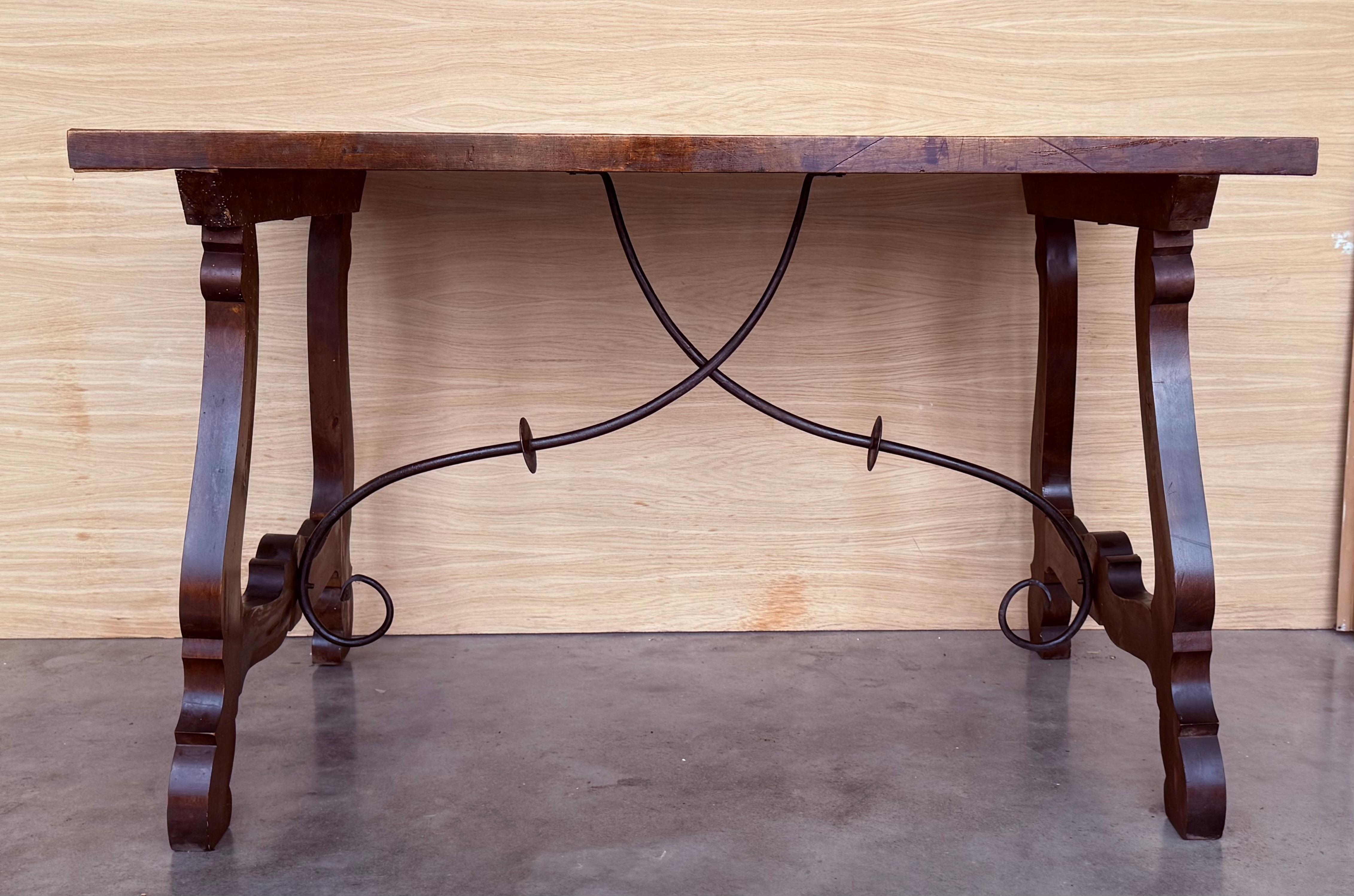 Dining table made of walnut with carved lyre legs and heavy top. 
The lyre legs are very thick.
Beautiful iron stretcher, Spanish, 19th century.