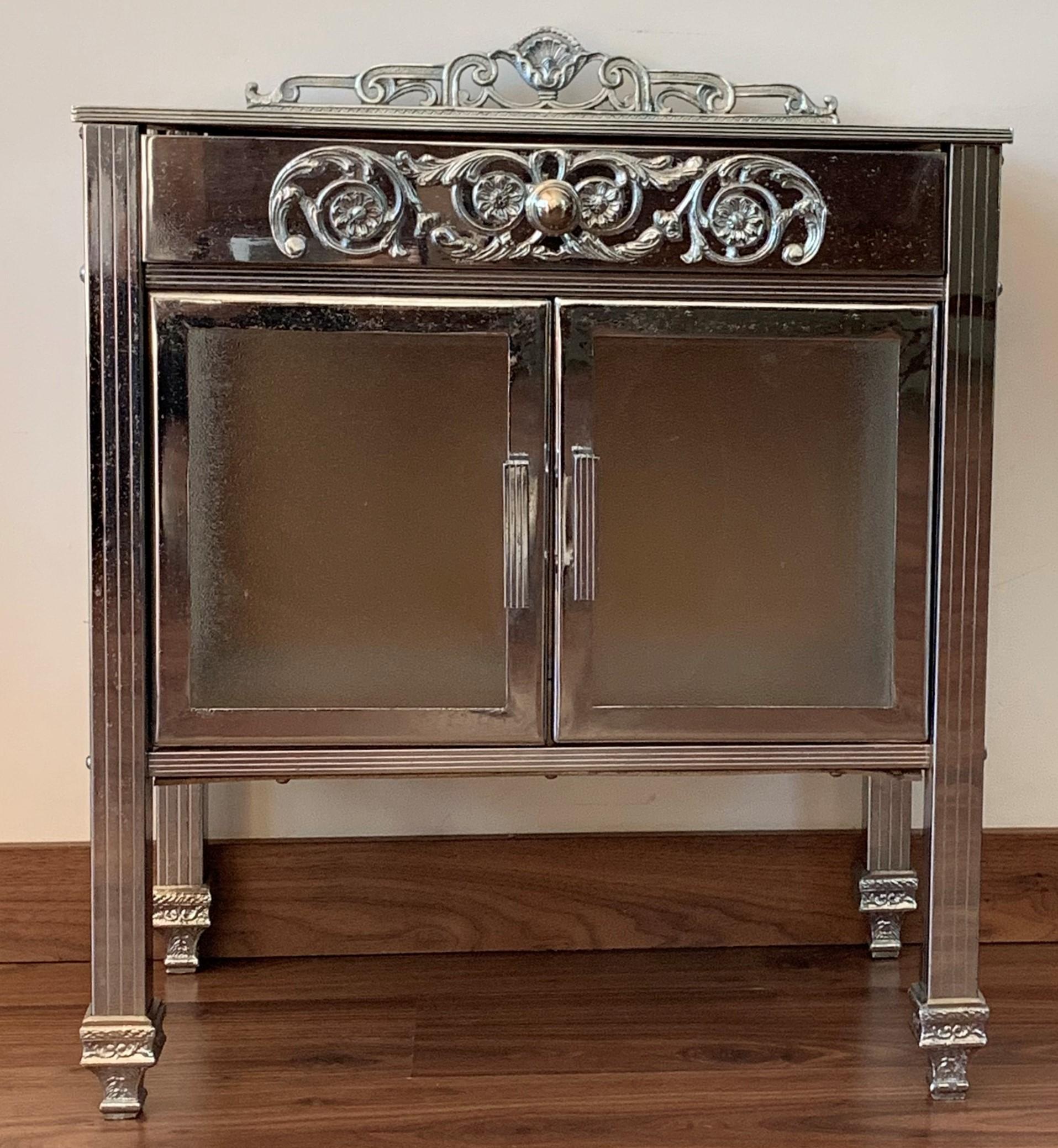 Beautiful 20th century French polished brass side table or nightstand or étagère with rollers, black glass top, and drawer and crest adorned with floral copper details around.