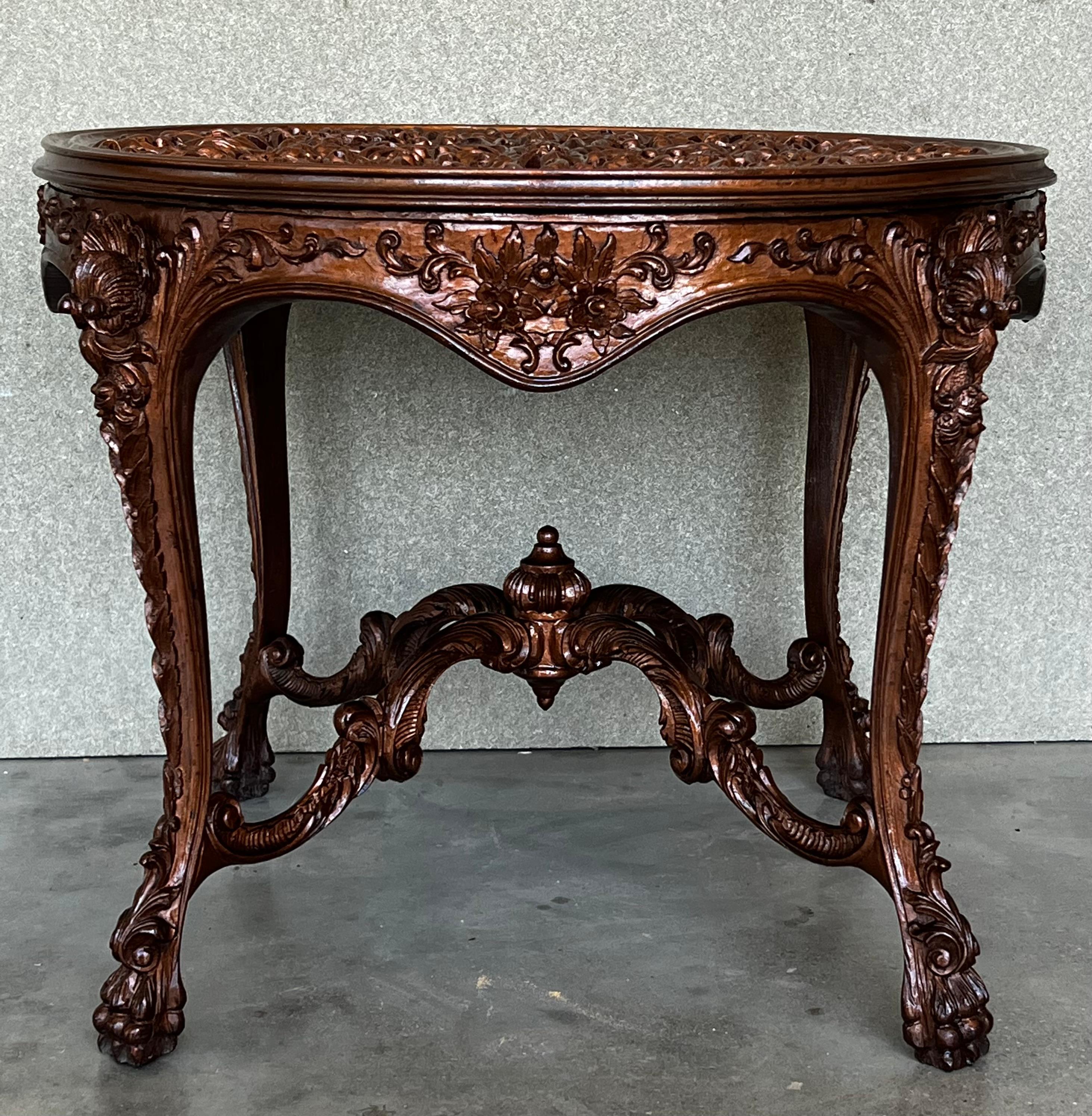 An Italian Rococo style round side table with a richly carved top and base from the 20th century. The apron is adorned on all sides with typical Mariano Garcia motifs . The table is on four cabriole legs with scrolled feet, adorned with acanthus