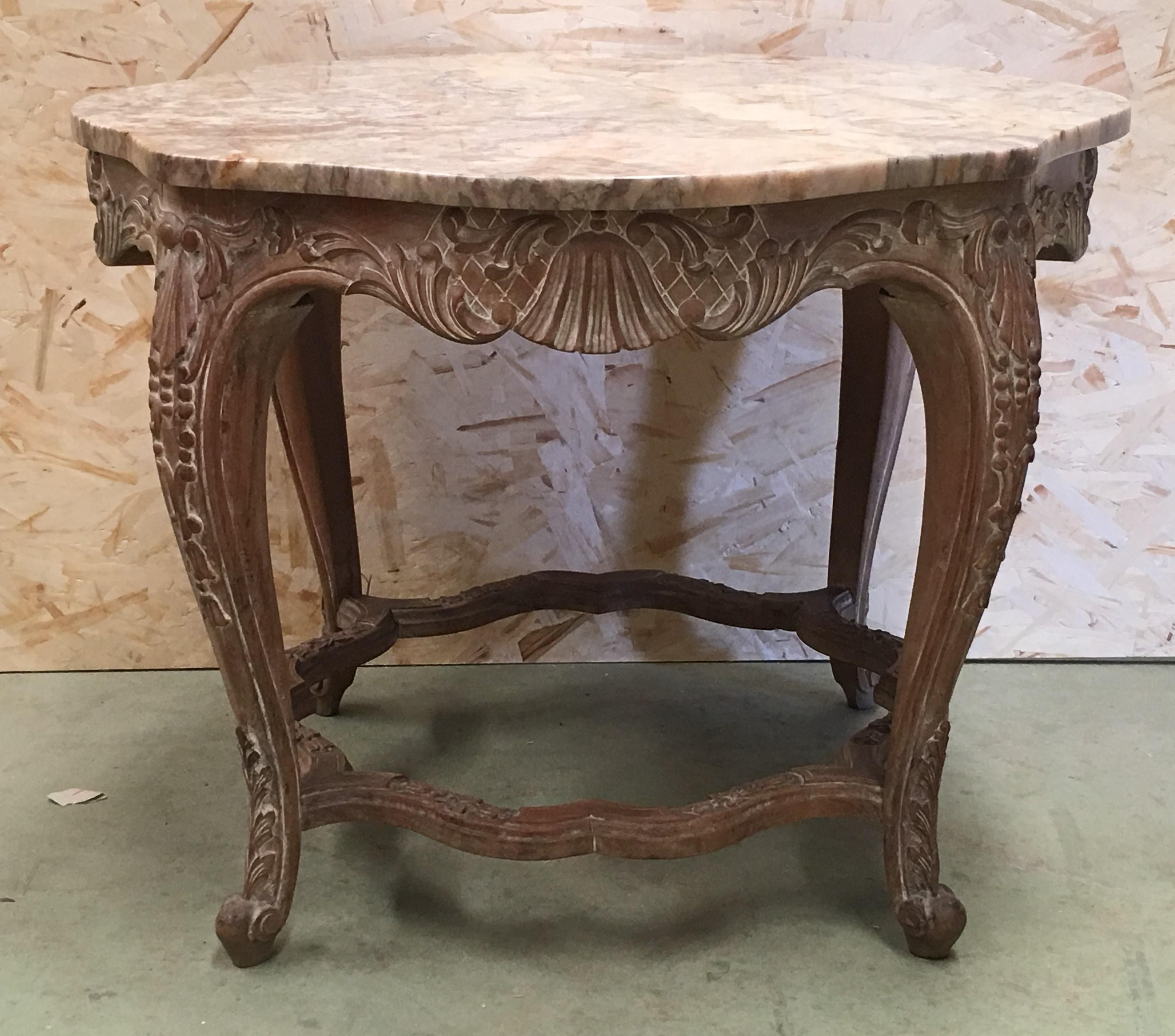 An Italian Rococo style round side table with Siena marble over a richly carved base from the 20th century. This exquisite Spanish side table features a “giallo Siena” marble top (yellow veined marble) over a hand-carved, painted base. The apron is