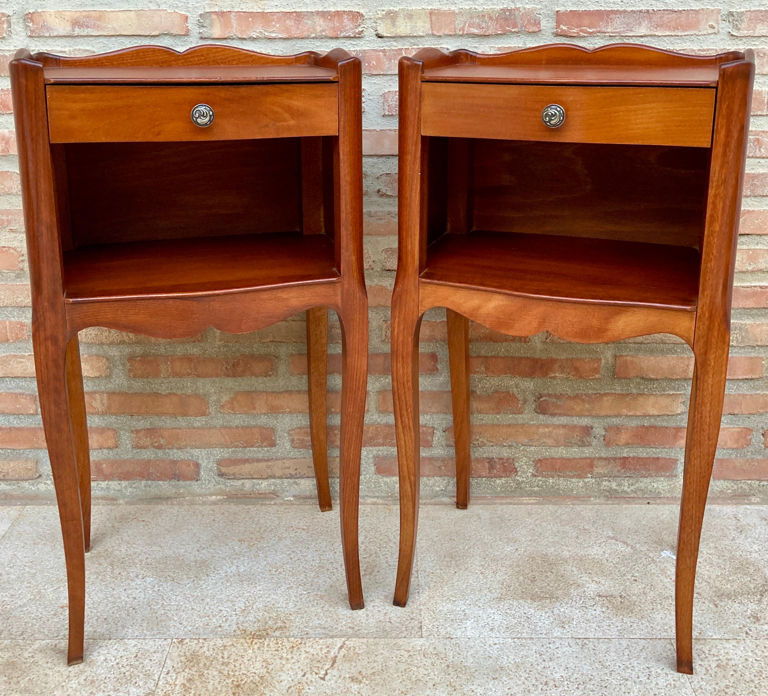 A pretty pair of French walnut nightstands and one drawer with open shelf, circa 1940. 
Pair of French Louis XV style walnut bedside tables from the early 20th century. This pair of French 'tables de chevet' were created in the early 20th century,