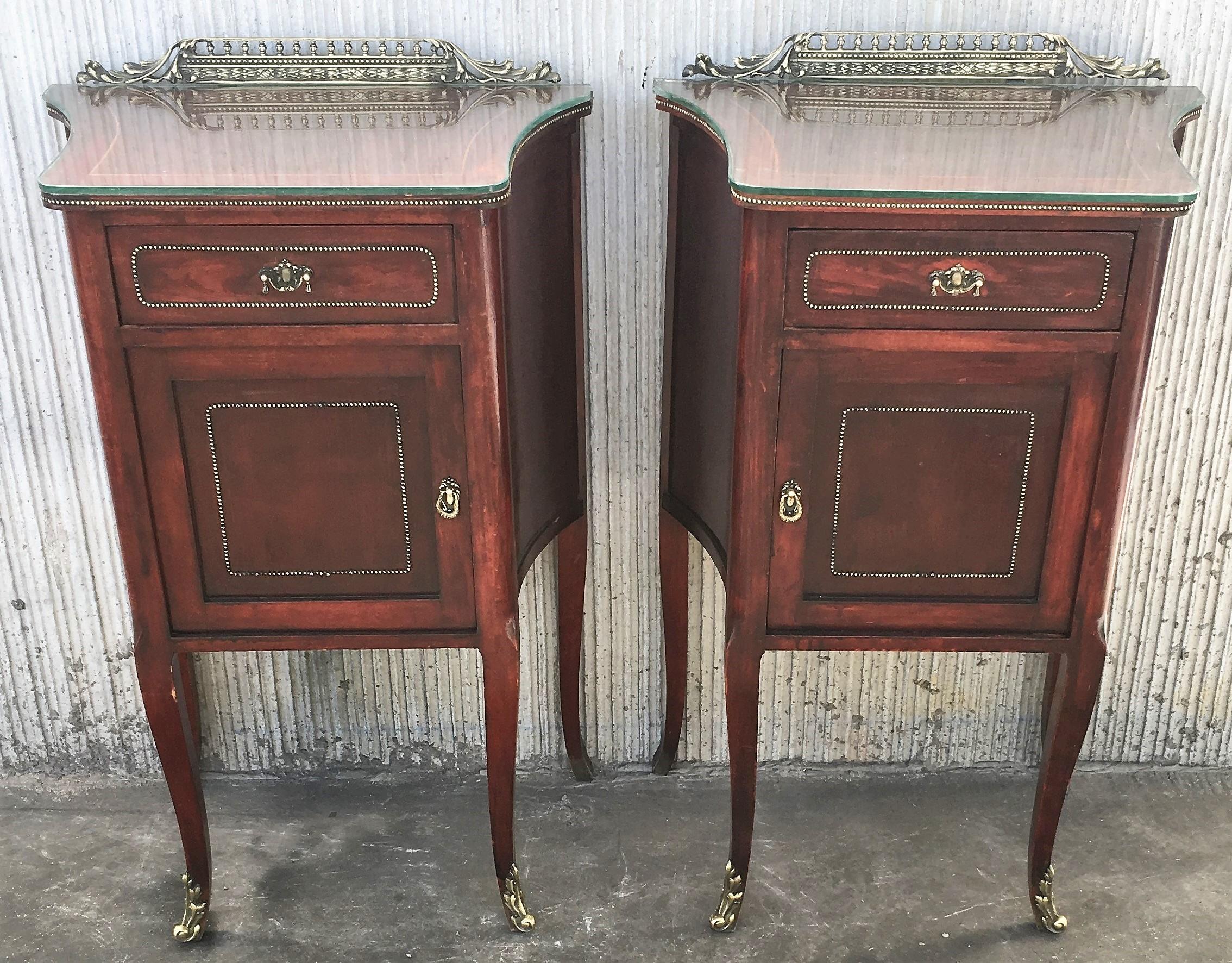 20th French Mid-Century Modern pair of nightstands with glass top and bronze crest.