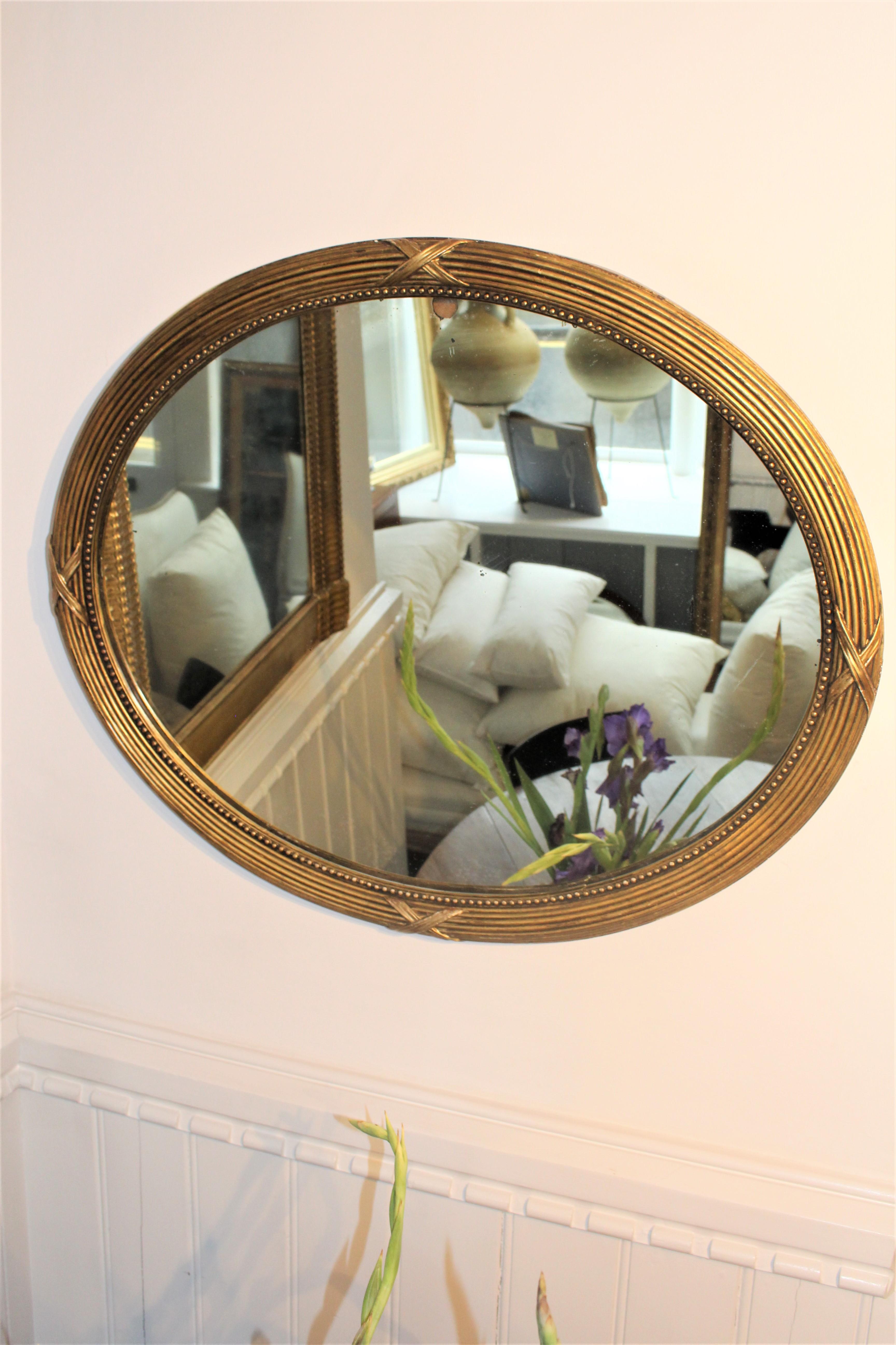 Oval French Art Deco gilt mirror with internal beading, original mercury glass plate and ribbon decorations,.
circa 1930s
Can be used portrait or landscape.

Condition:
The giltwood frame is in good condition with no beading missing. Just a few