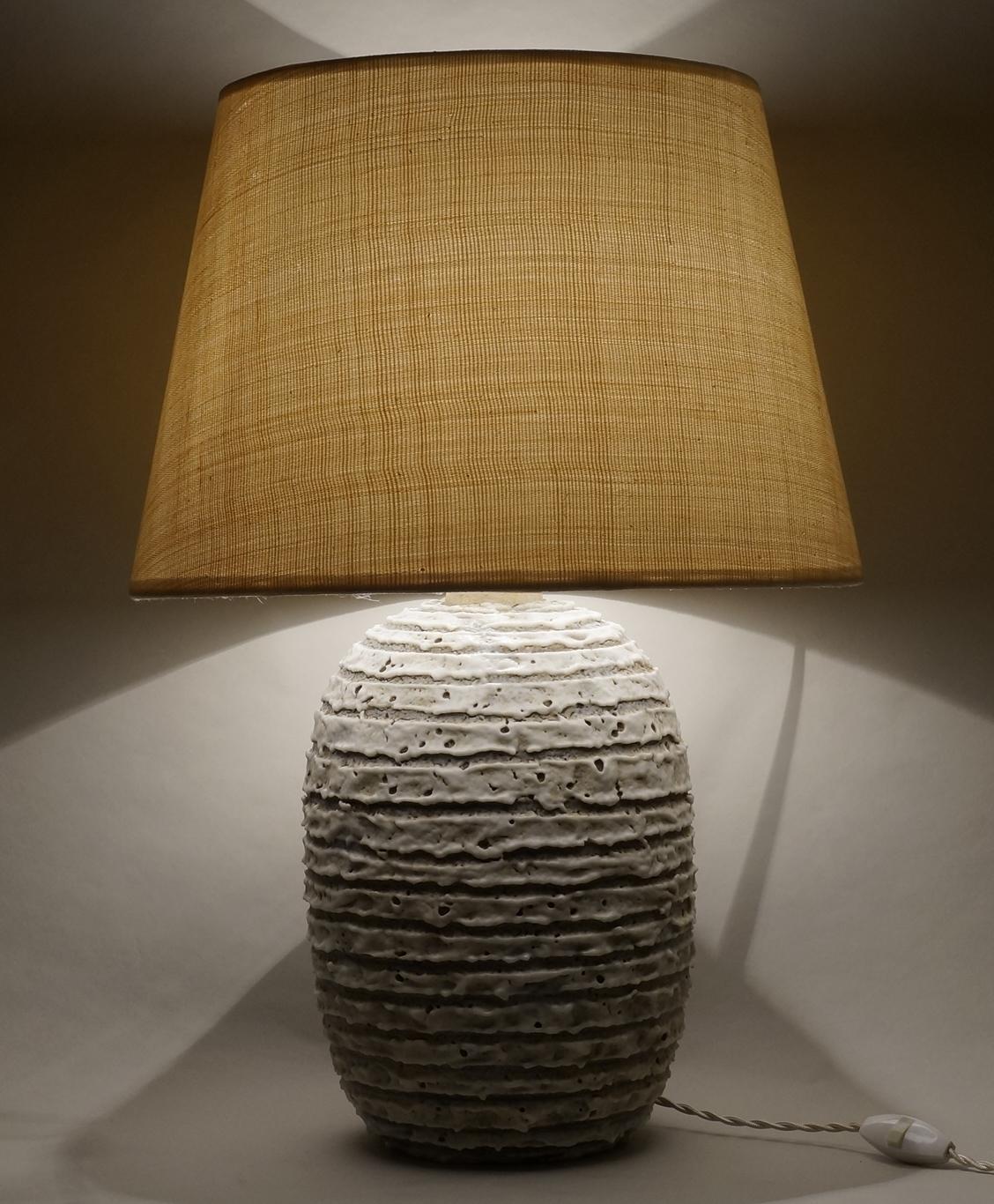 Ethnic white ceramic table lamp with scarification
custom made fabric lampshade in abaca, rewired with twisted silk cord.

Measures: Ceramic body height 30 cm - 11,8in.
Height with lampshade 56 cm - 22in.