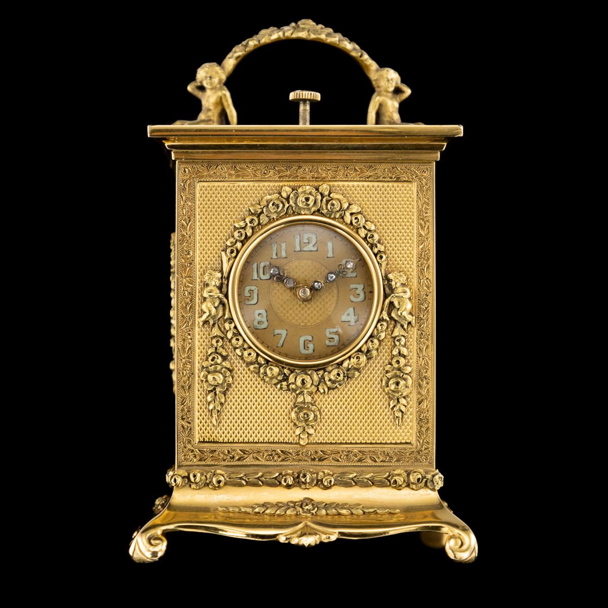 Antique 20th century English miniature 18-karat gold, quarter repeating carriage clock, round dial set with luminescent numerals and old-cut diamond hands, the 18-carat solid gold case decorated with engine-turned panels and applied with putti and