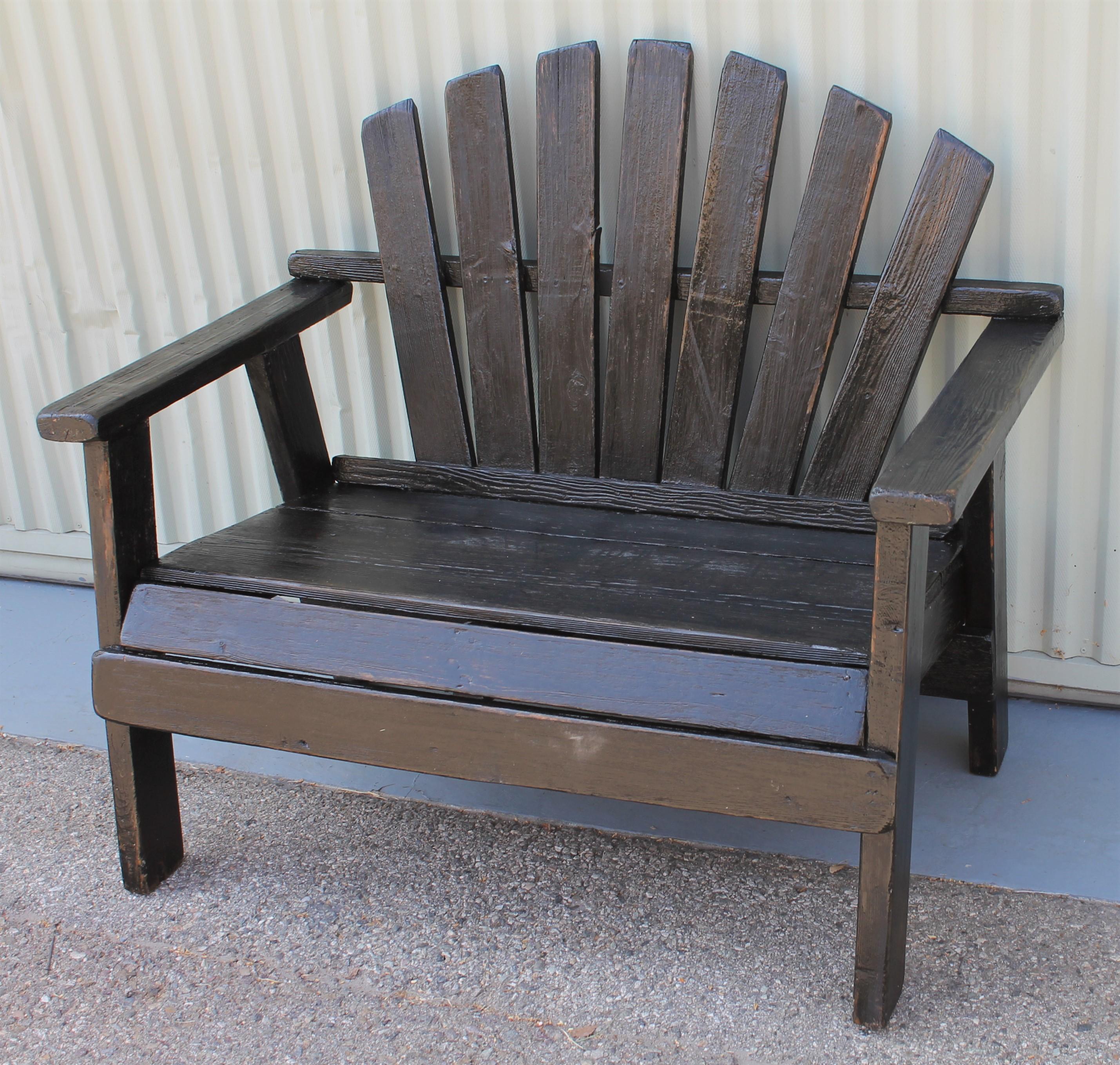This fine bench is in old black worn paint with a coating of outdoor weather protector. It can be flat or satin surface but protects from rain or beach salt water air born. This settee comes from a mid-western cabin.