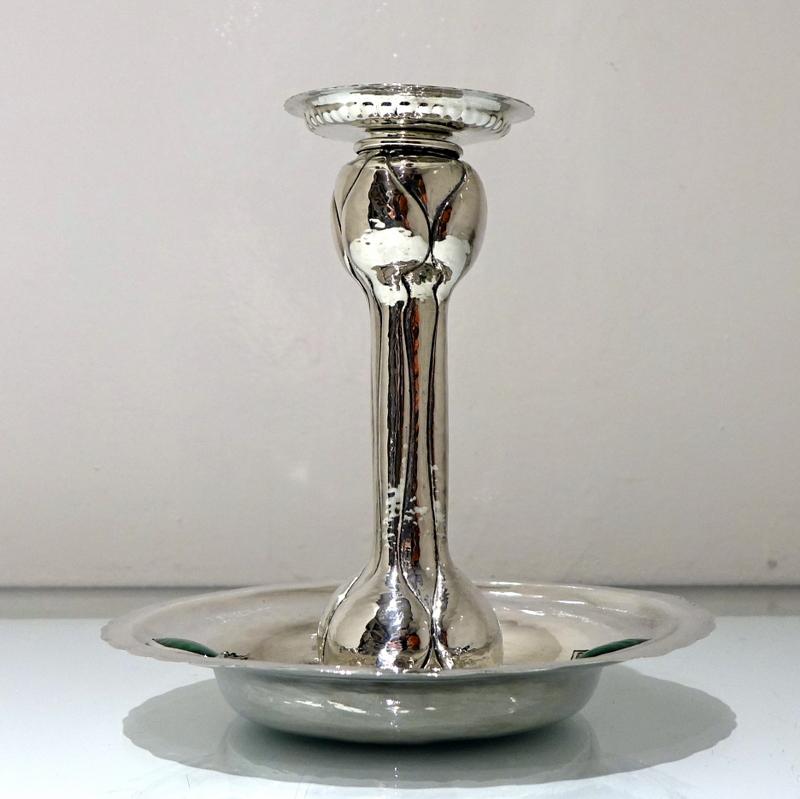A highly collectable Art Nouveau silver chamberstick designed with an elegant “hammered” finish and three oval enameled plaques. The central column has floral designs for additional decoration.

 

Weight: 9.3 troy ounces/290 grams

Height: 7