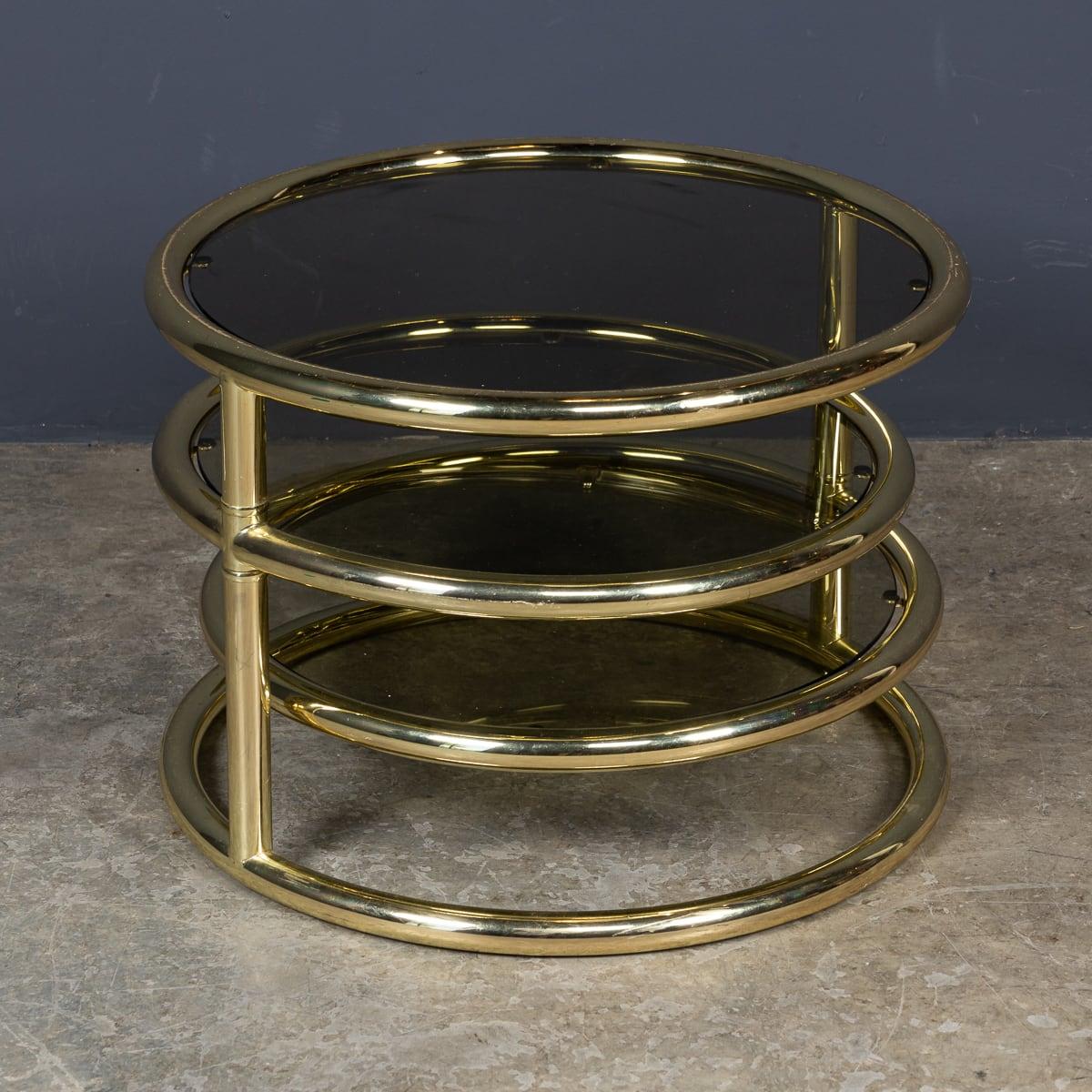 A 20th Century American made three tier circular swivel table. Designed by Milo Baughman, the tables are designed with a three tier table top allowing the user to swivel the upper section towards them or away from them according to their needs. It
