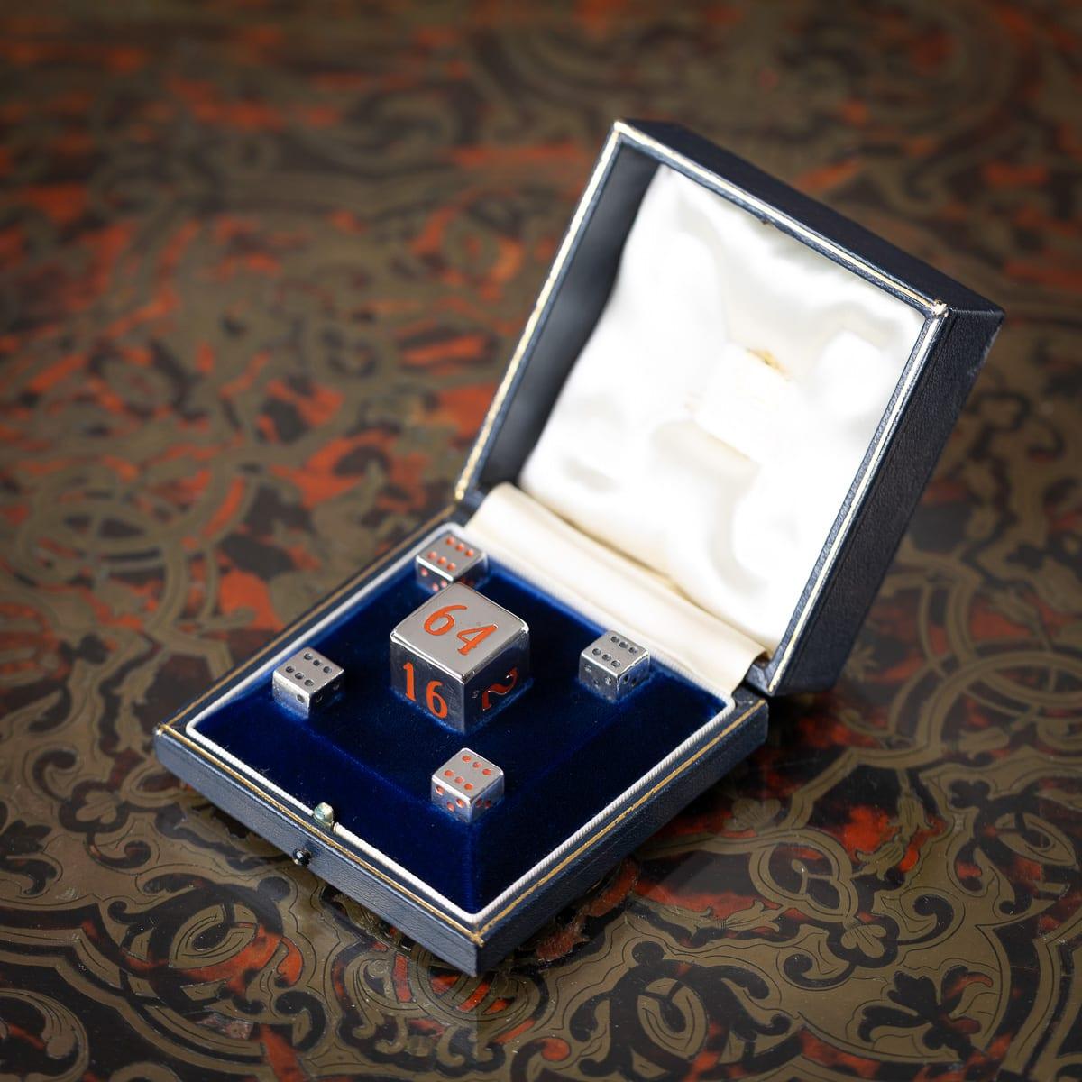 Un superbo set di dadi da backgammon in argento massiccio inglese del XX secolo. Ogni dado è realizzato in argento massiccio e decorato con punti di smalto rosso o nero, mentre i dadi più grandi presentano numeri in smalto rosso. Il set è presentato