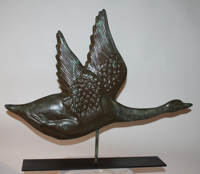 This weather vane of a Canadian Goose in flight has a wonderful aged patina and is in fine condition. It comes with a custom made iron stand. The form is the very best of its kind.