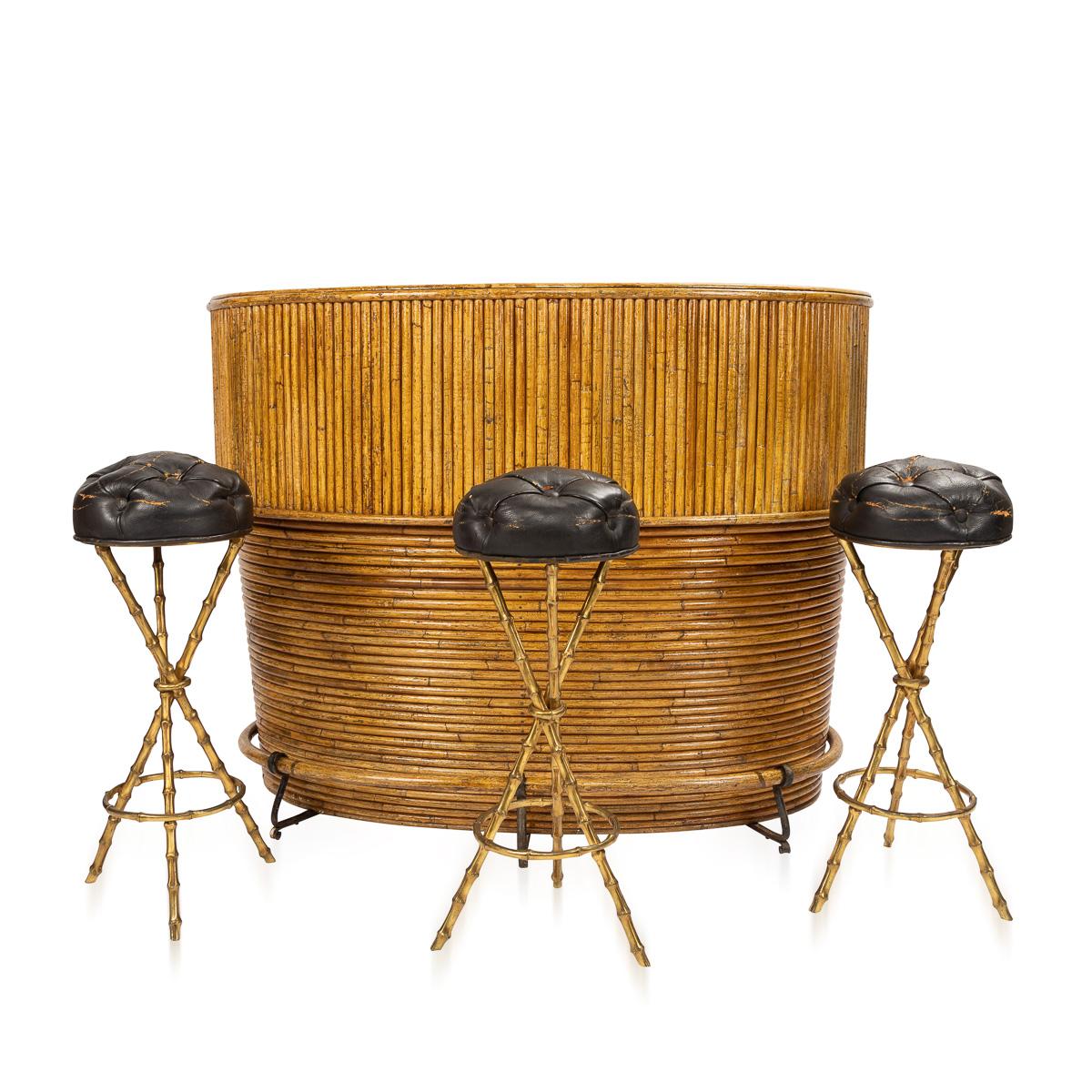 Iconic mid-20th century French Bamboo cocktail bar with a faux leather top and a shelf on the inside for storage and gilt brass faux bamboo tripod bar stools with original buttoned leather seats by Jacques Adnet.

An icon of luxurious French