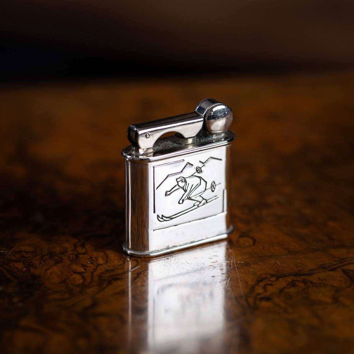 Briquet de fantaisie français du 20e siècle, chromé, présentant un skieur gravé en mouvement sur une face et un motif de moteur tourné sur l'autre. Estampillé à la base 