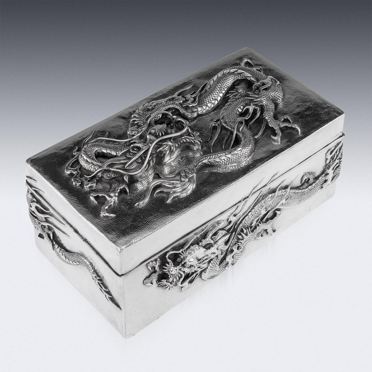Antique early 20th century Japanese Meiji period solid silver cigar box, double skinned body, sides and lid are embossed in high-relief with water dragons and applied with flowing whiskers on hand hammered ground, dark wood lined base and interior.