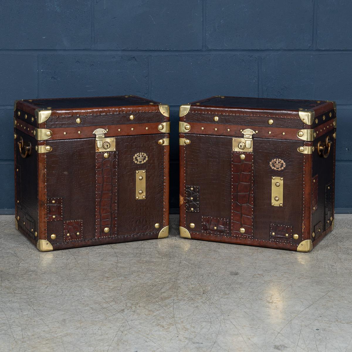 A pair of leather-clad Army and Navy style trunks, crafted in England in the late 20th century, they exude rugged sophistication and timeless appeal. Inspired by traditional military campaign trunks, they feature sturdy leather exteriors with robust