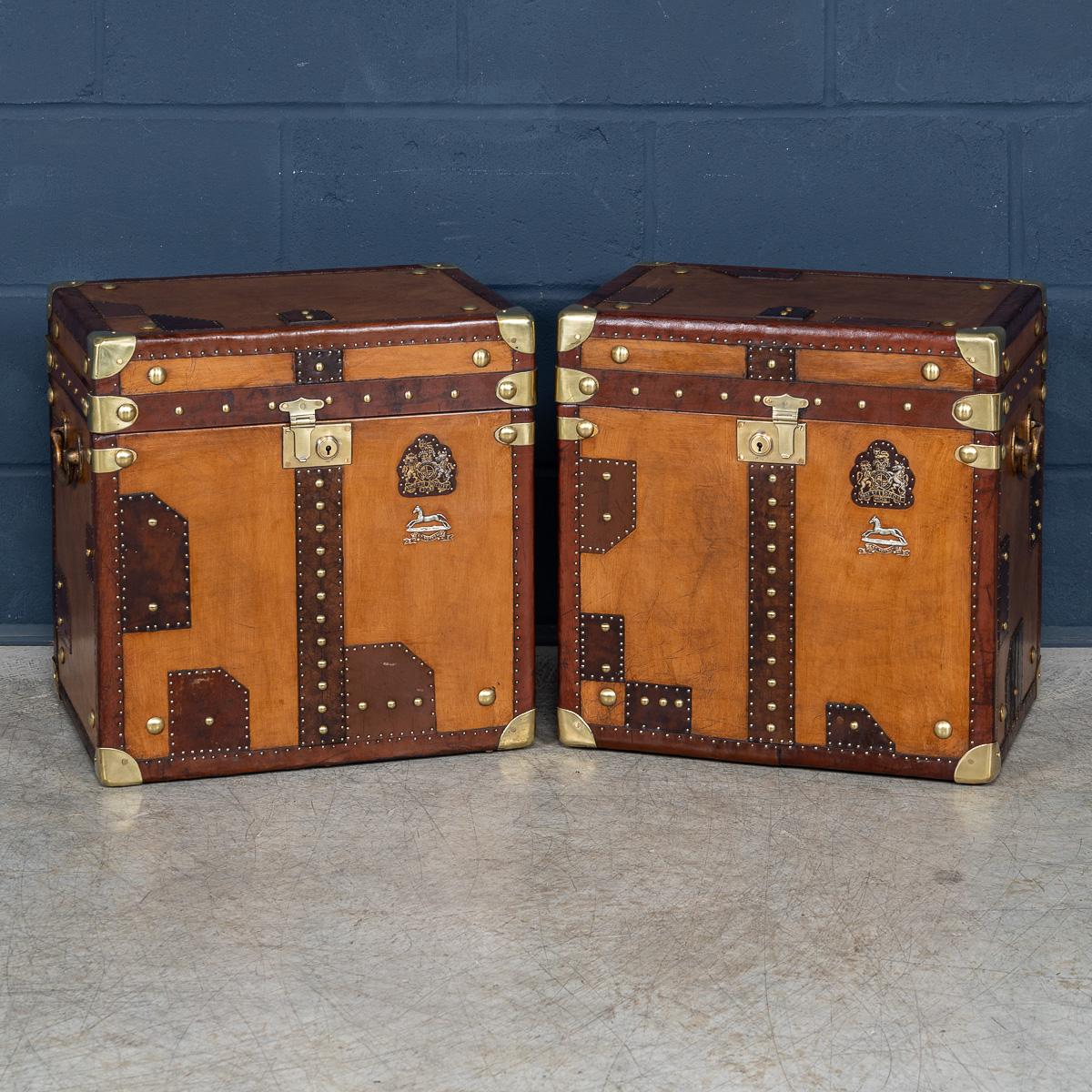 A pair of leather-clad Army and Navy style trunks, crafted in England in the late 20th century, they exude rugged sophistication and timeless appeal. Inspired by traditional military campaign trunks, they feature sturdy leather exteriors with robust