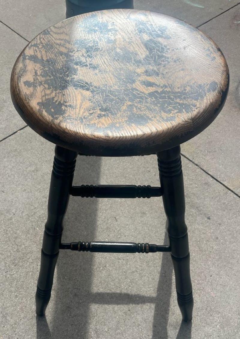 This fine splay leg original black painted industrial stool swivels and rotates all the way around. It is heavy and solid oak wood underneath the painted surface. Probably from an old shoe factory.
