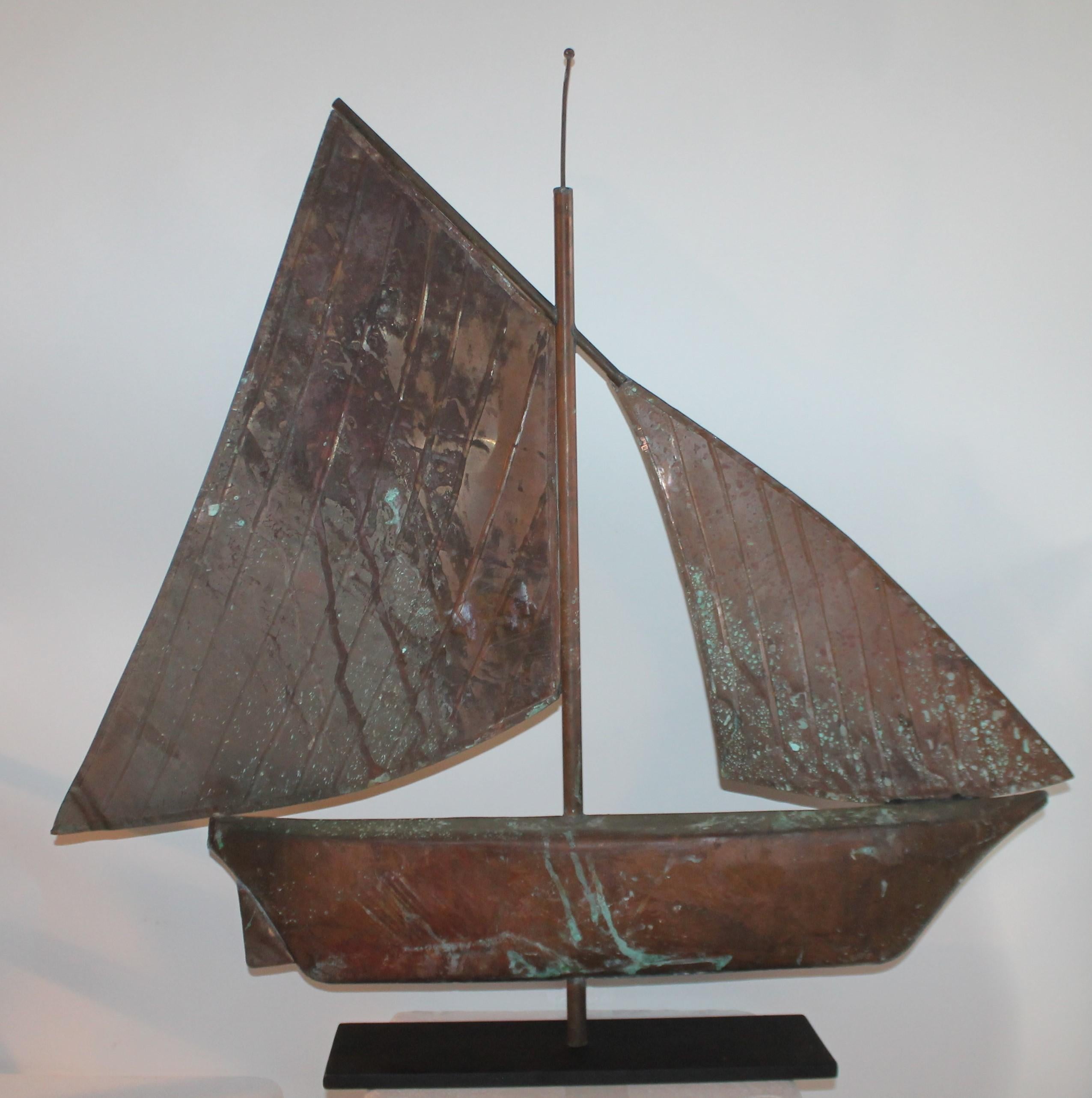 Early 20th century copper sailboat weather vane with amazing patina to the body and sail. This sailboat weather vane has a custom made iron base. Would make for a stunning mantel (fireplace) piece or center piece.