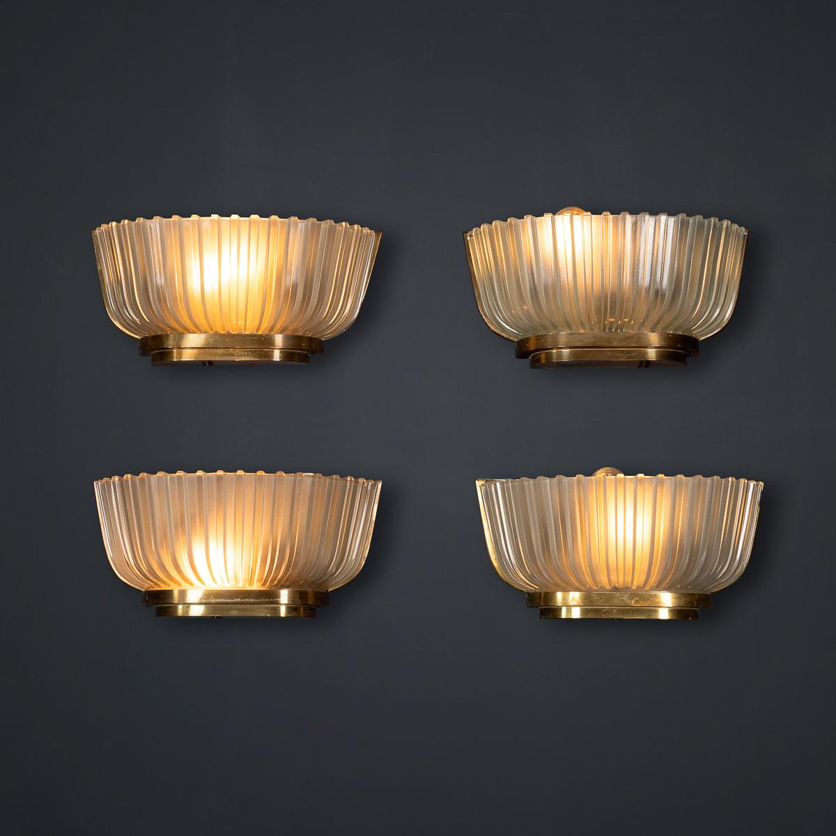 Ensemble de quatre appliques murales en verre opaque cannelé de Murano du 20e siècle sur des montures en laiton, chacune équipée de deux ampoules. Ces élégantes lampes sont attribuées à Archimede Seguso, vers 1940.

CONDITION
En tant qu'articles