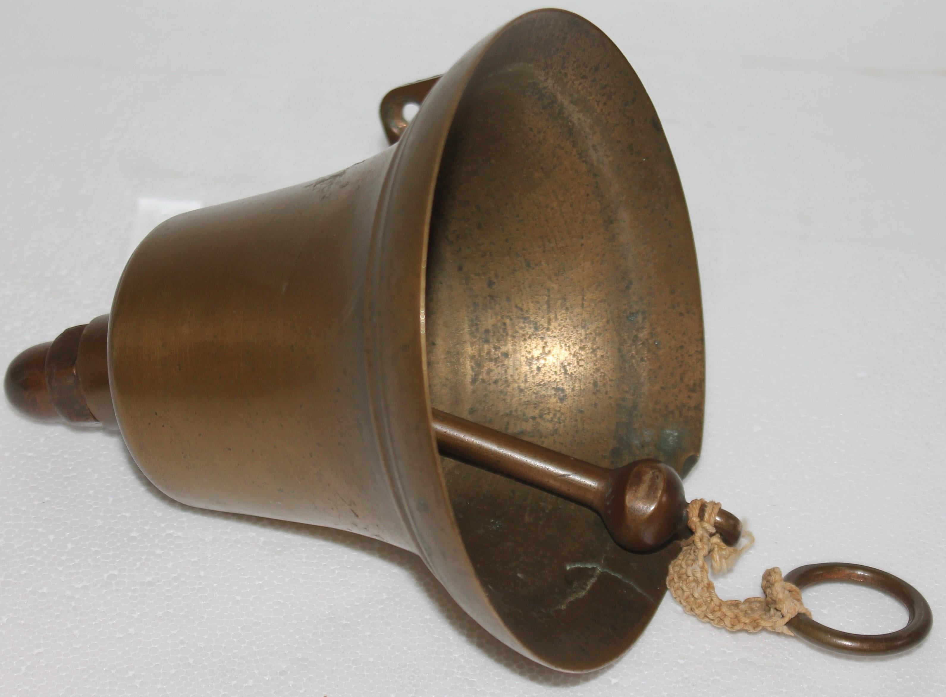 20thc Ships brass bell with rope for a ringer. This could be a dinner bell on the front of a house or mounted on the front of the house.