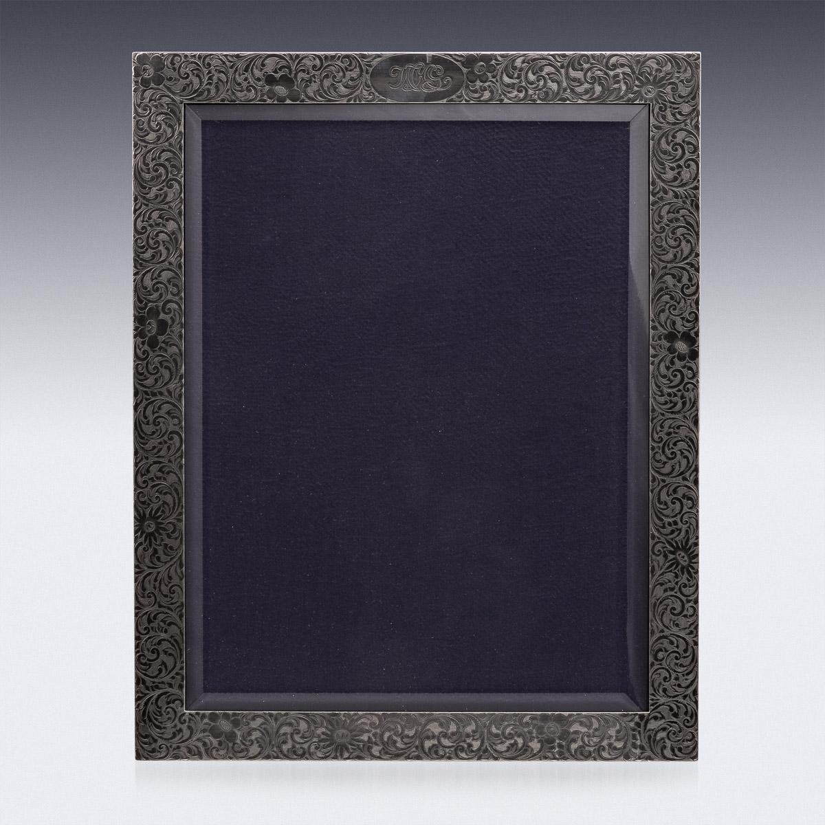 Antique early 20th century American solid silver photograph frame, particularly large, engraved with scrolls and flowers, the top with the initials WHG, mounted on a wood back with easel support, front with beveled glass to protect the photo.